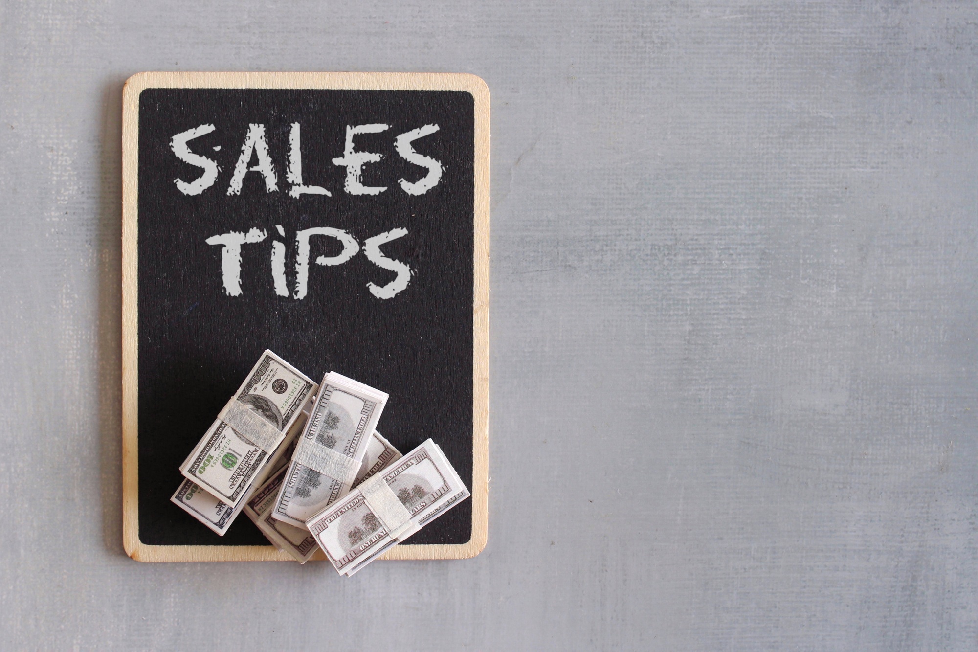 Top view image of banknotes and chalkboard with text SALES TIPS.