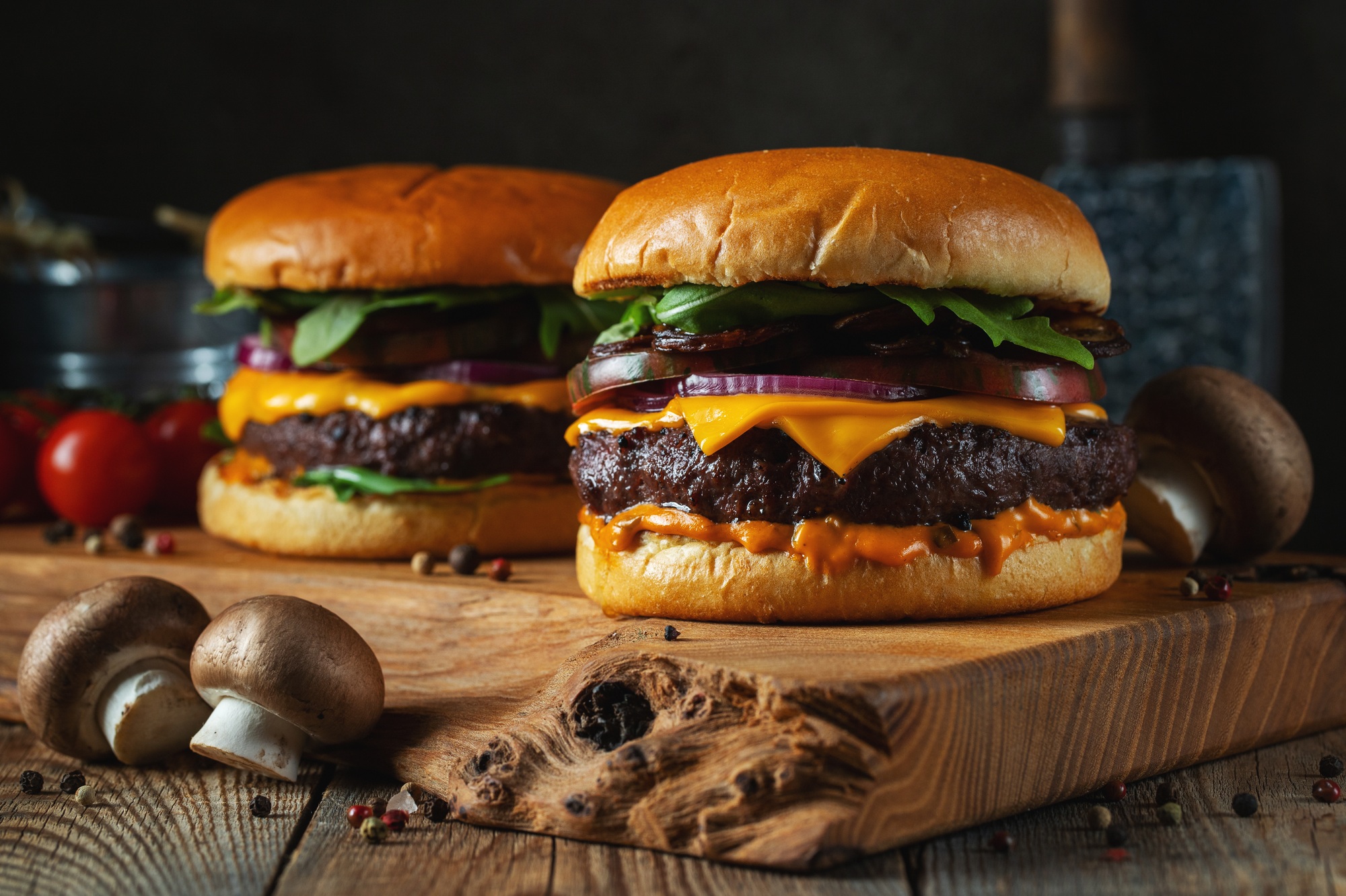 Two delicious homemade burgers of beef, cheese and mushrooms on an wooden table. Fat unhealthy food