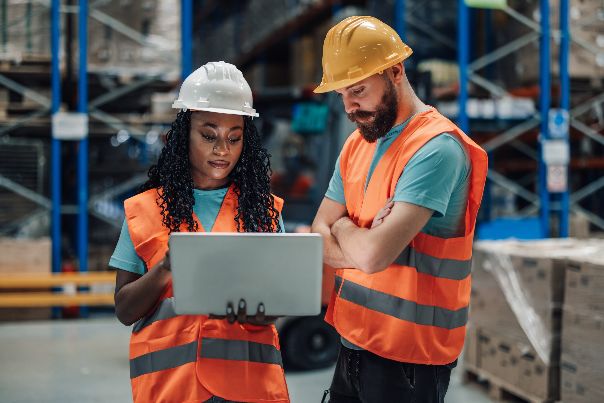Two multiracial workers concentrating on a laptop in a storage facility