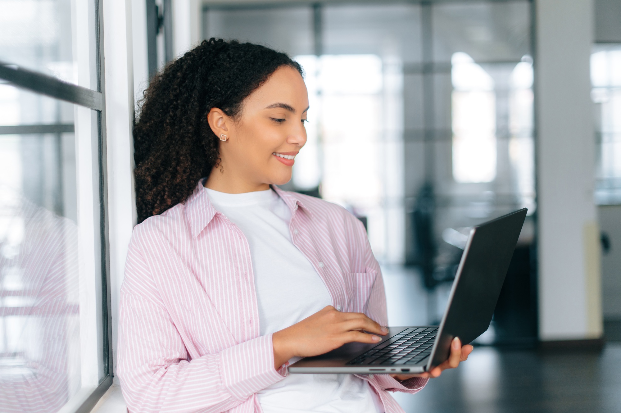 Using gadgets and devices. Pretty, successful brazilian or latino curly haired woman, software