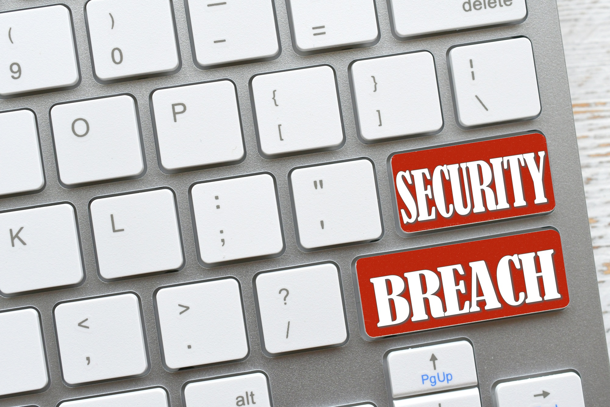 White computer keyboard with red keys that say Security Breach, online dangers Concept hacked