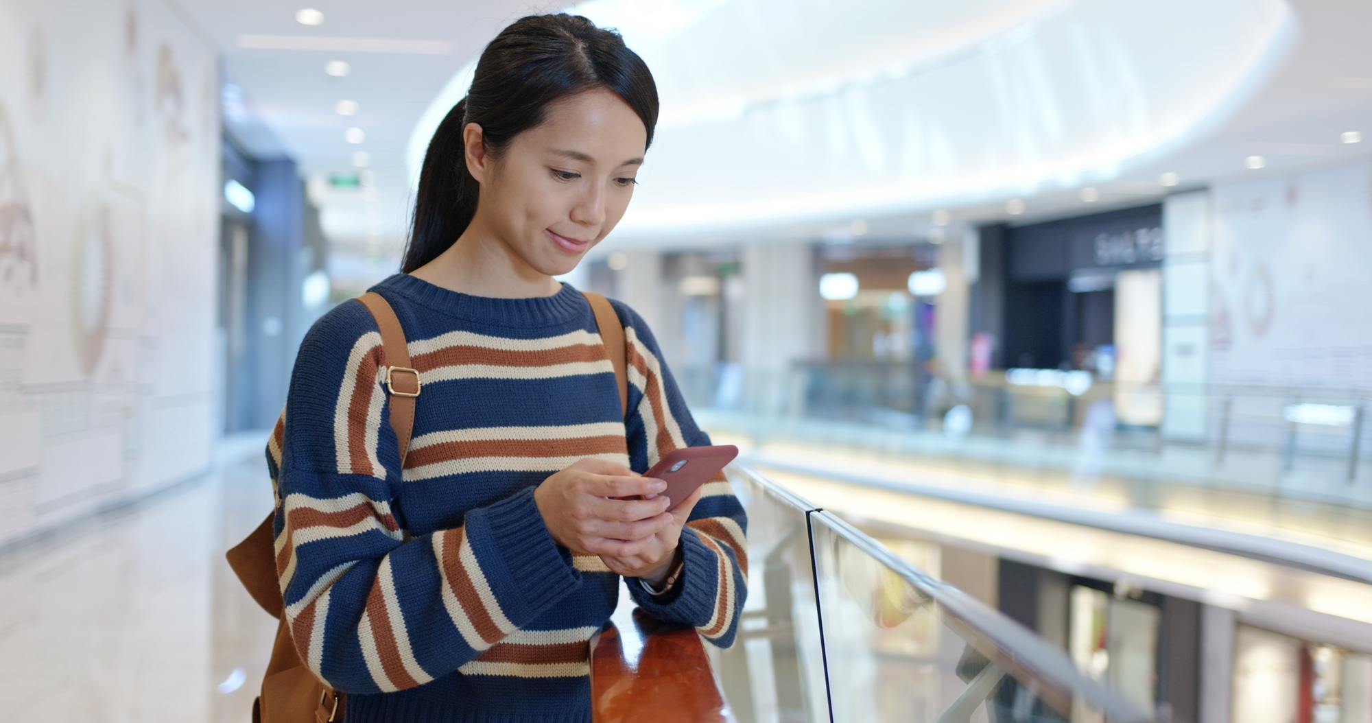 Woman check the sales on cellphone inside shopping center