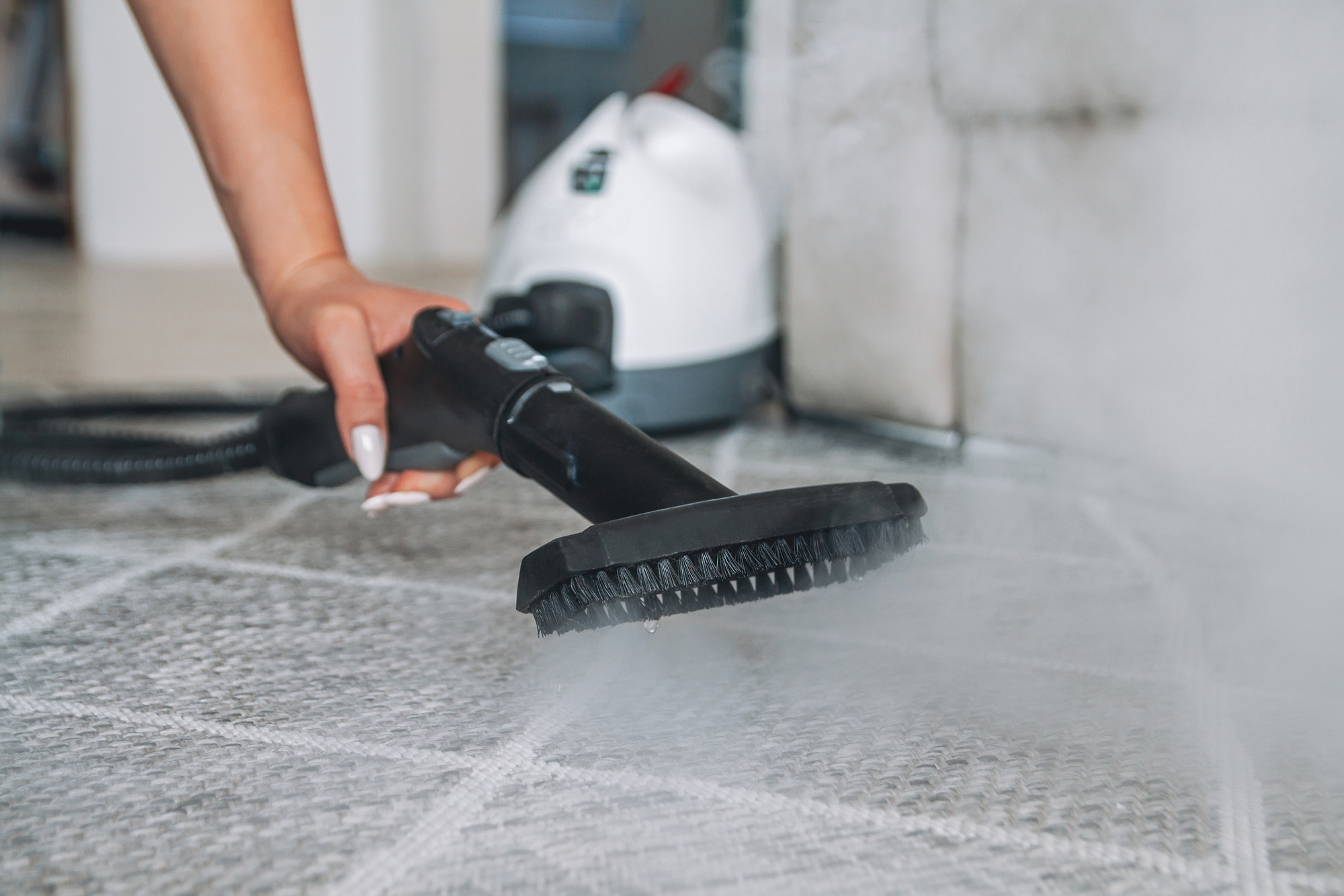 Woman cleaning carpet with a steam cleaner