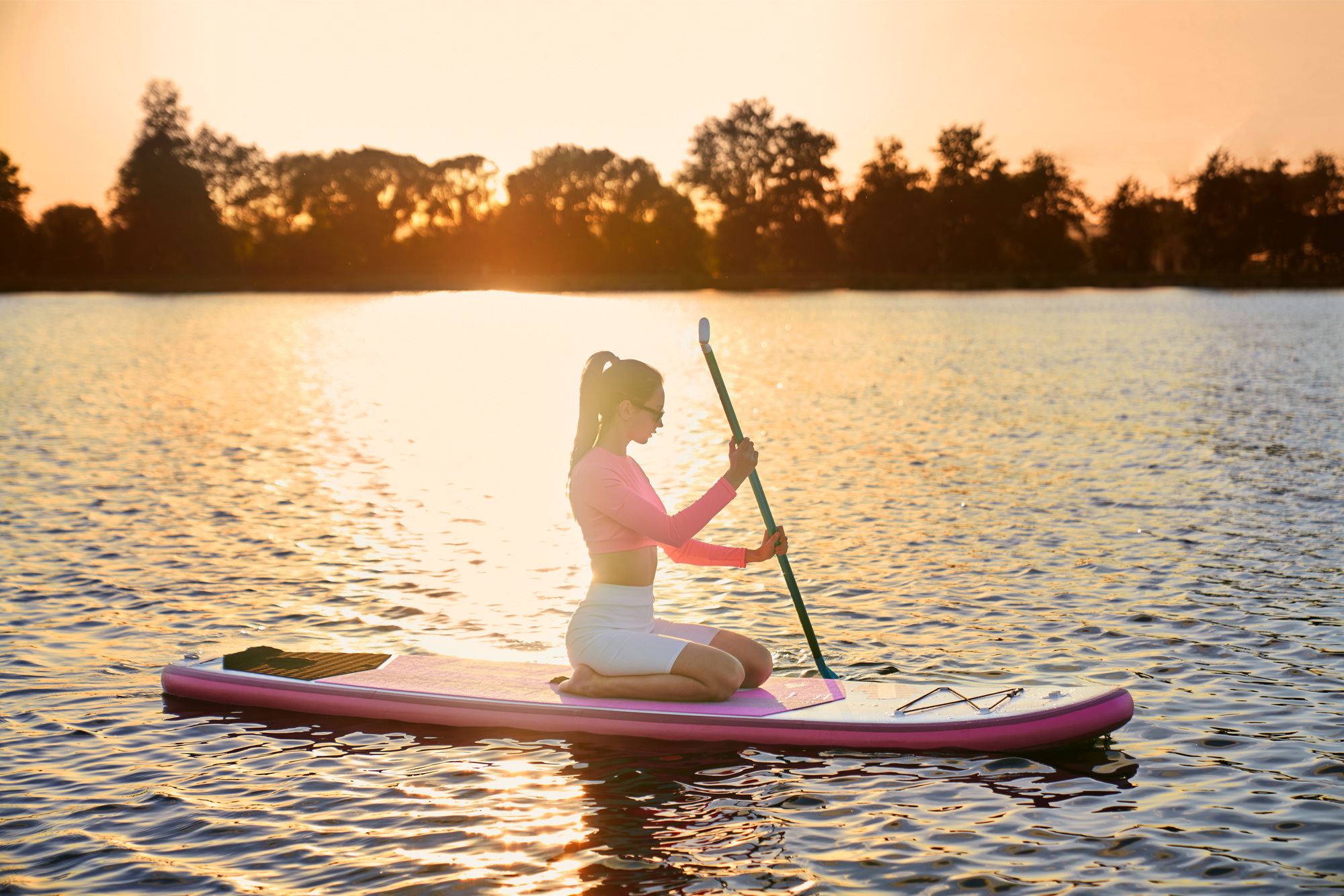 Woman in sportswear rowing with paddle on sup board