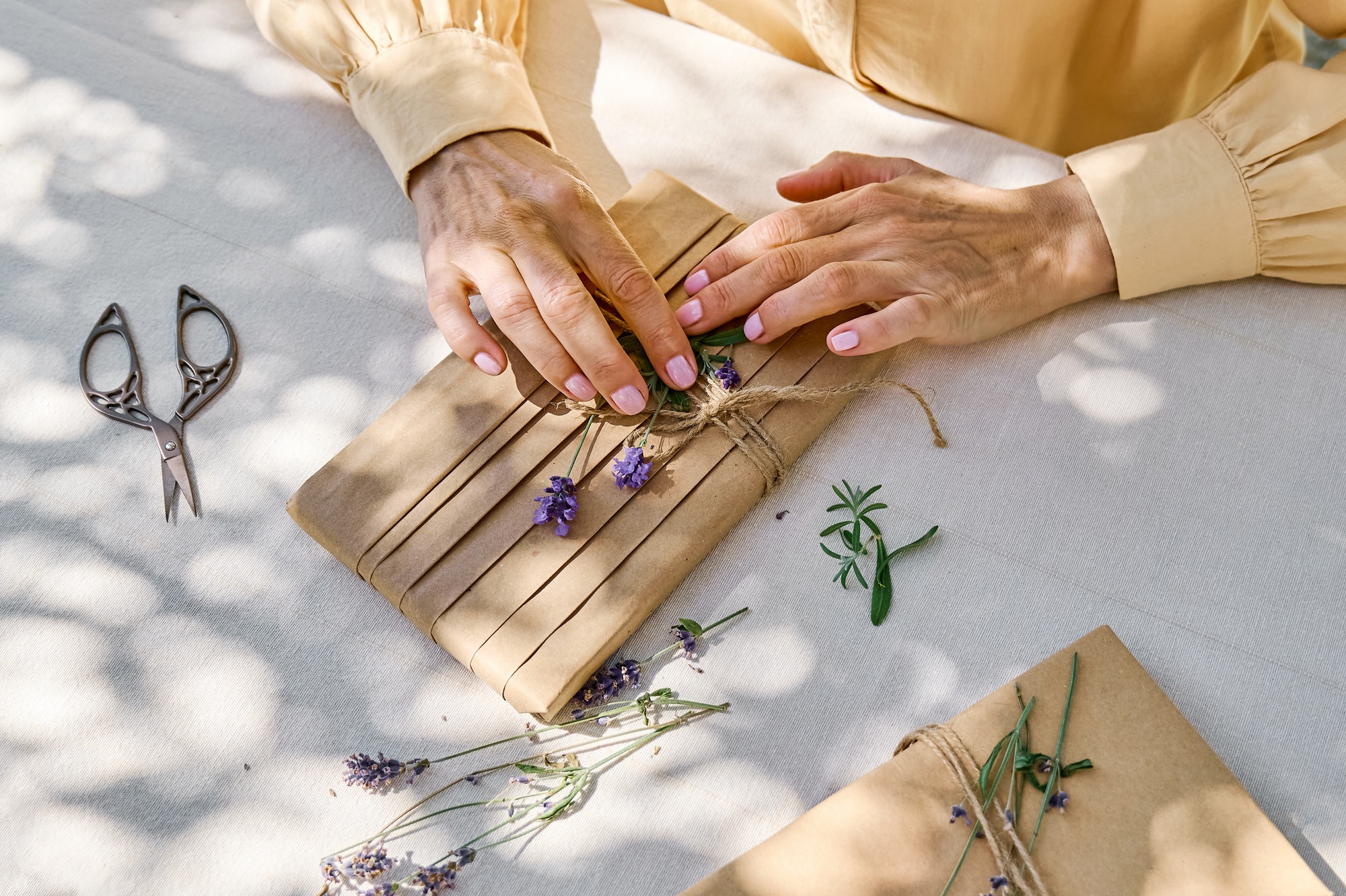 Woman making hand made gift package with craft recycled paper and dried lavender flowers