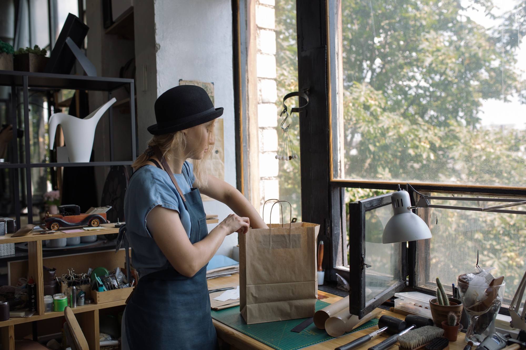 Woman packing craft products into paper bag in workshop for further sale.