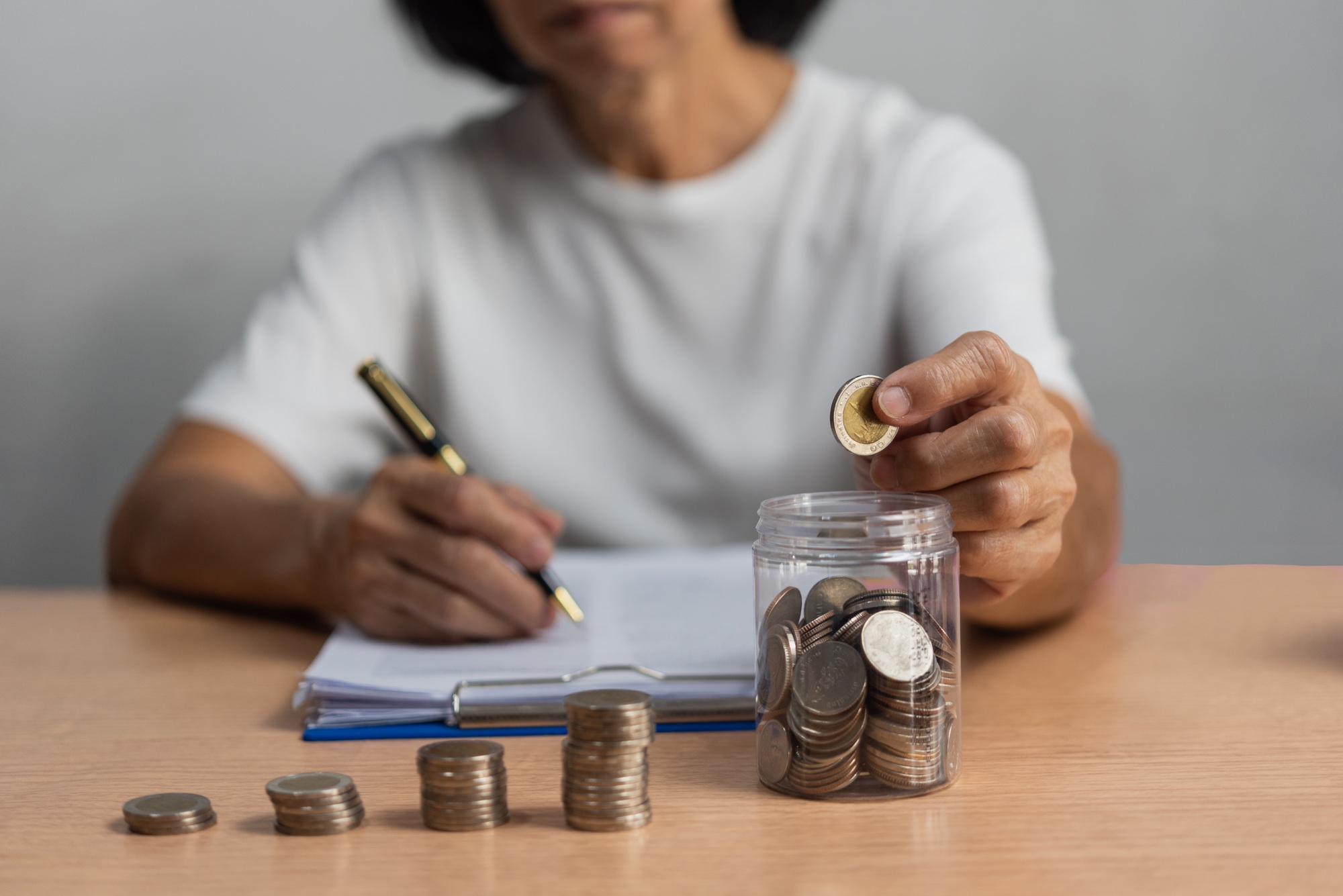 woman saving money with putting coins in glass, finance and accounting concept.