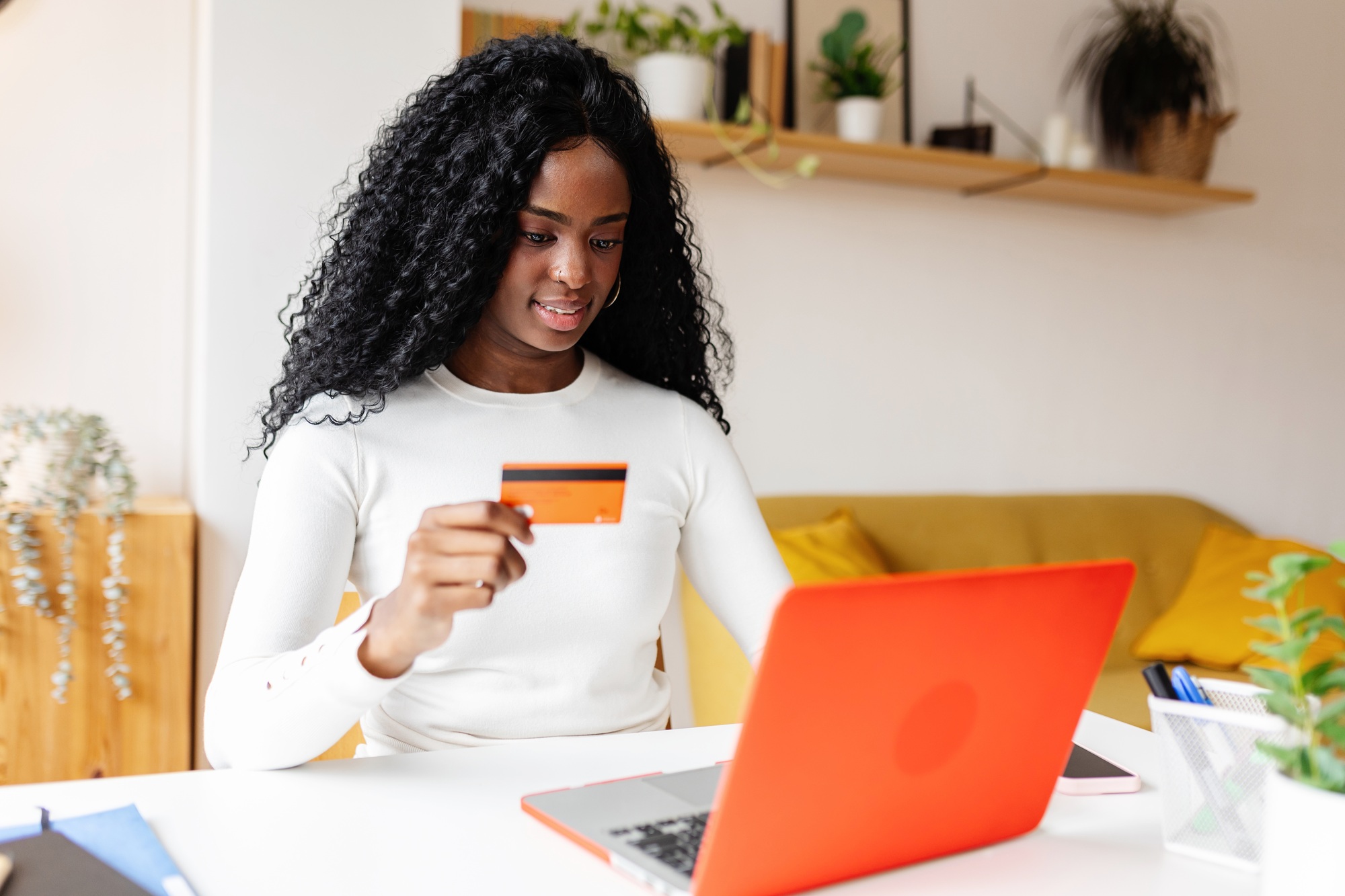 Woman using laptop and credit card for online shopping at home