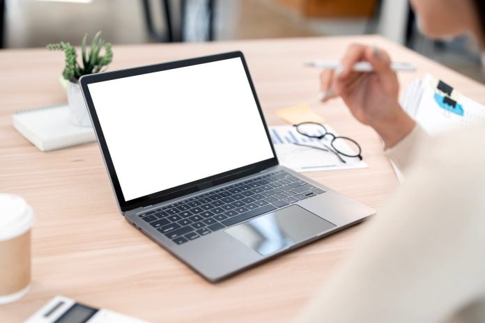 woman working on laptop computer at a table, typing on the laptop keyboard.