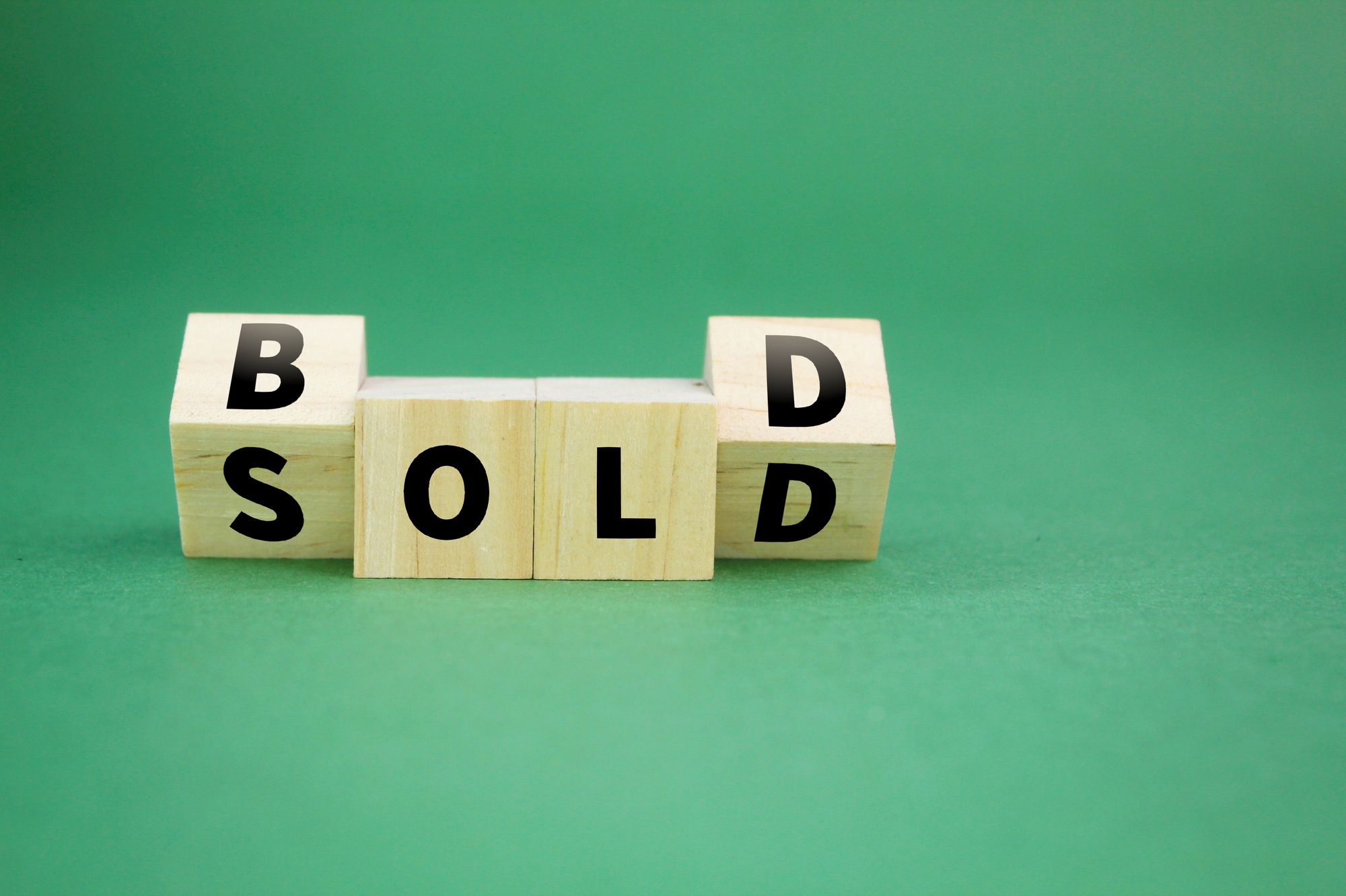 wooden cube with the word sold in bold.