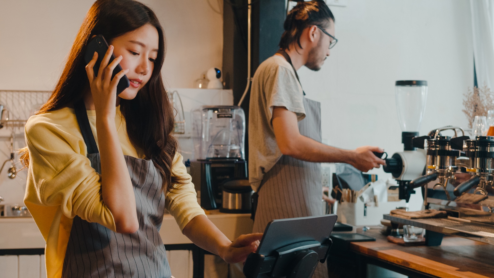 Young Asia female barista taking order by mobile phone.