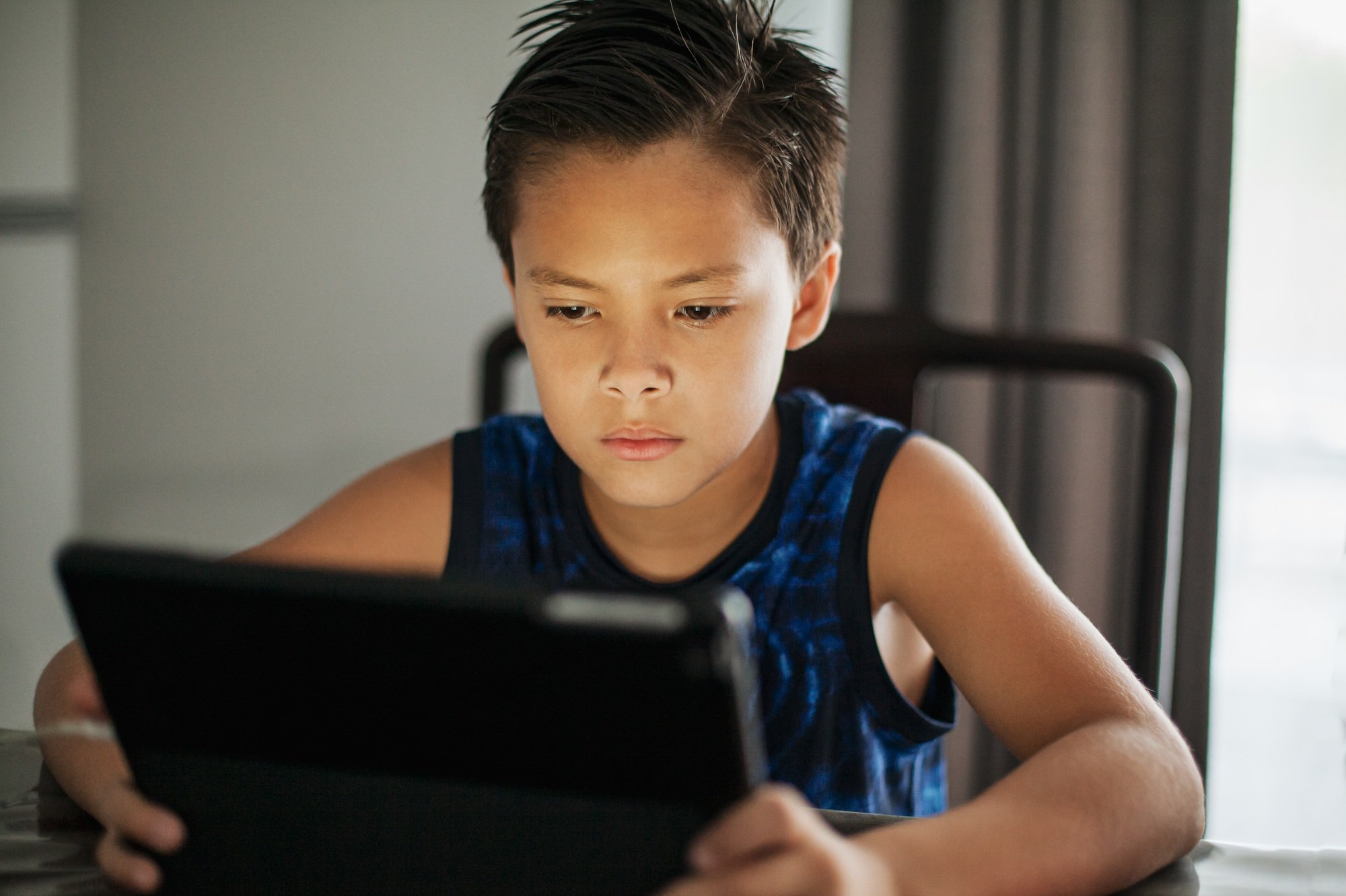 Young boy playing games online, concentrating looking on screen, childhood concept - Image