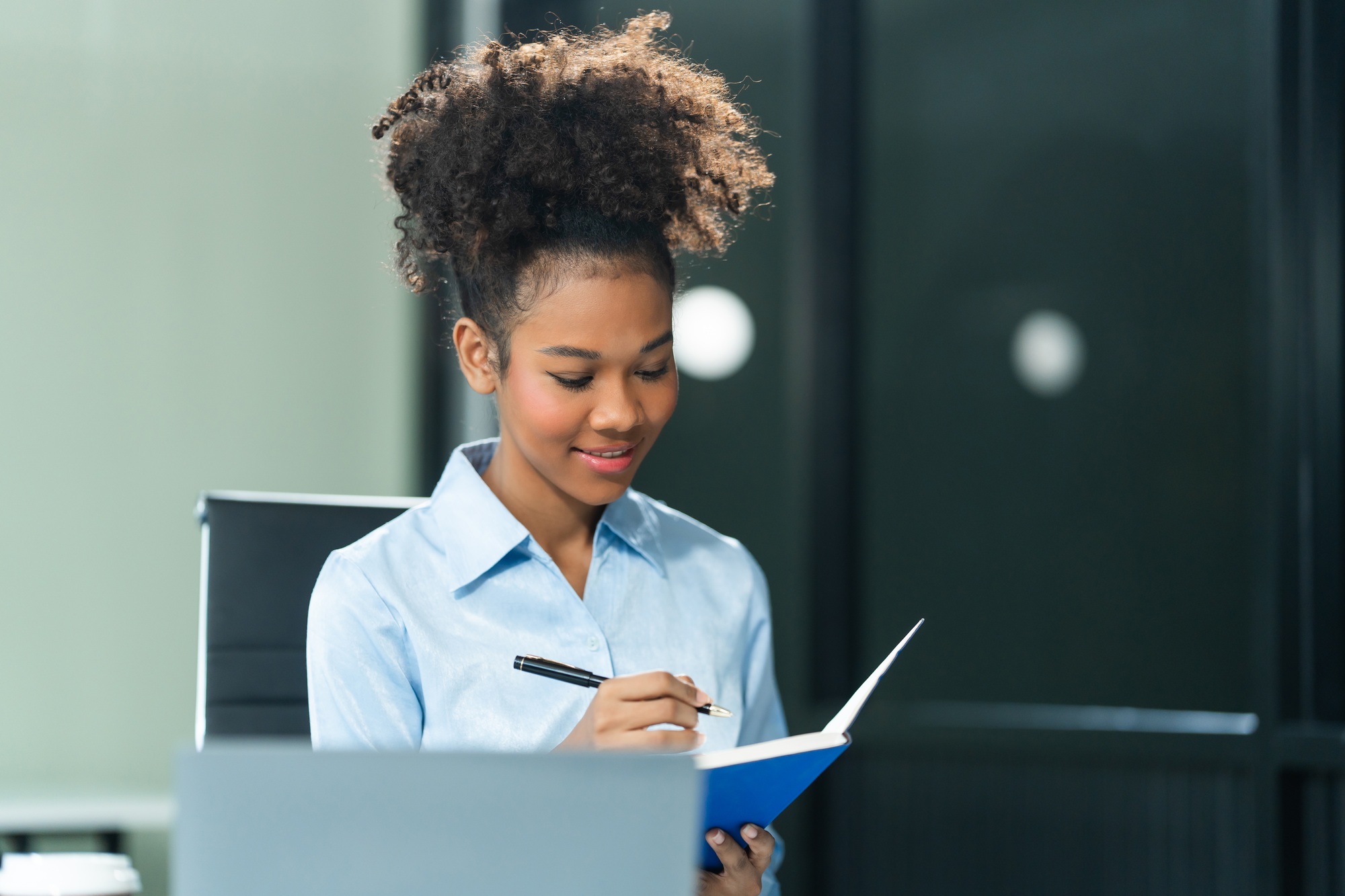 Young female African American in blue formal shirt with afro brown hair works as a Market Research