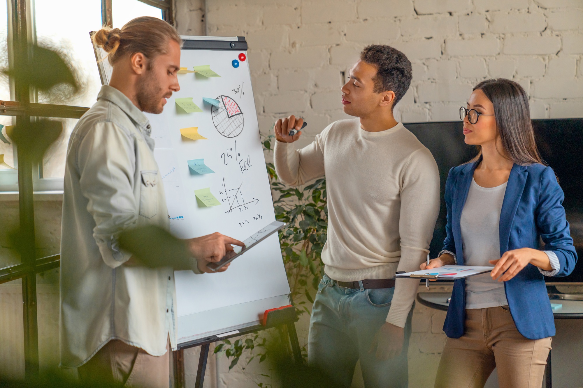 Young man standing by flipchart and giving presentation over new business startup