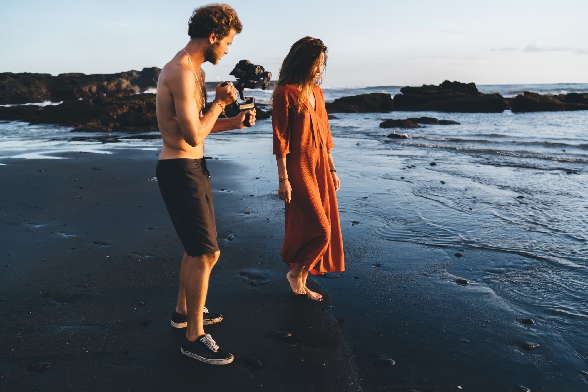 Young model and videographer with camera on seashore