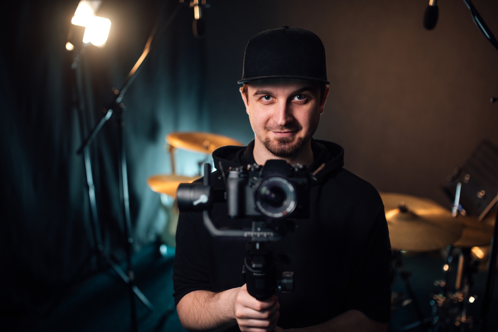 Young professional videographer holding camera on tripod.