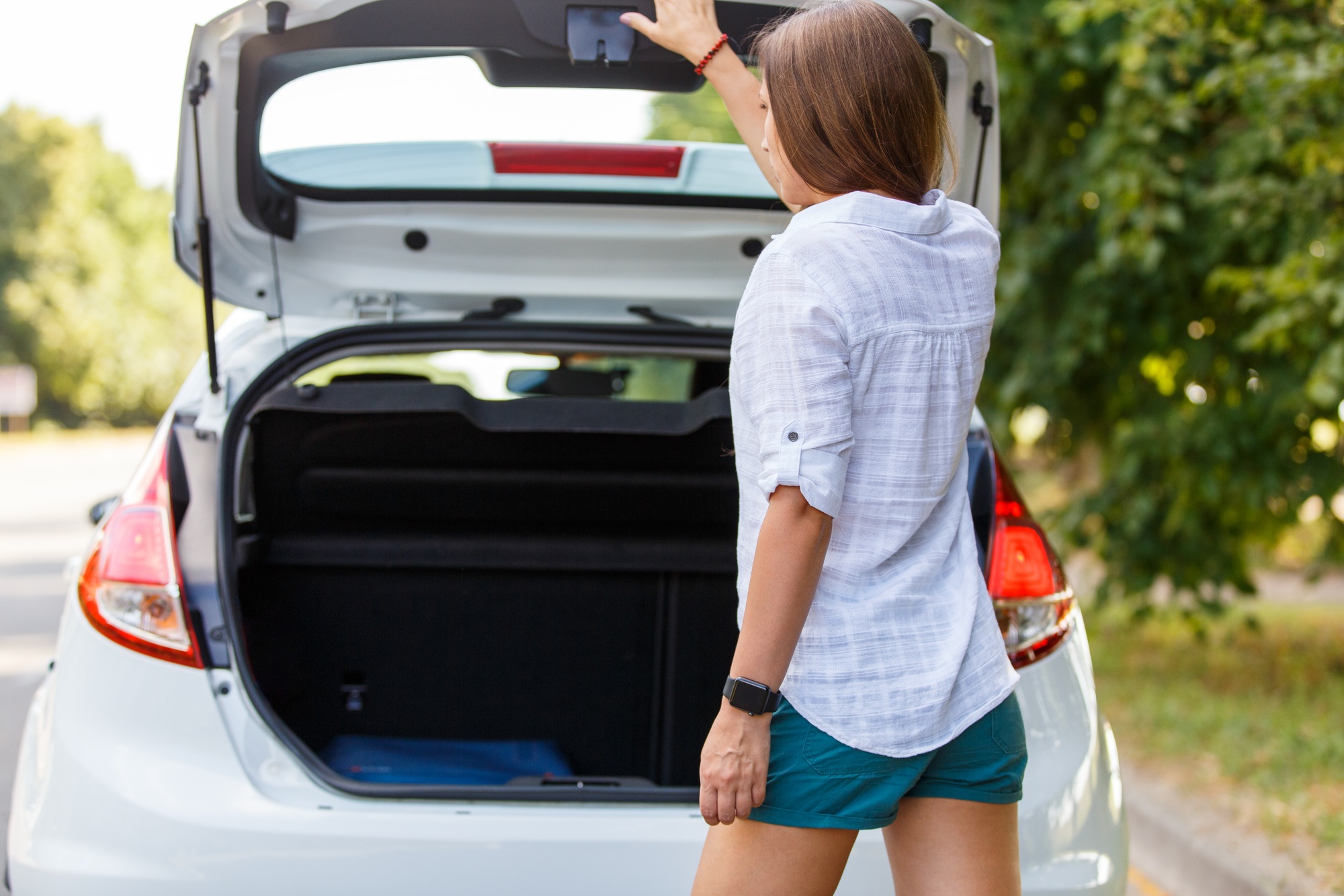 Young woman driver closing the trunk of the rental car