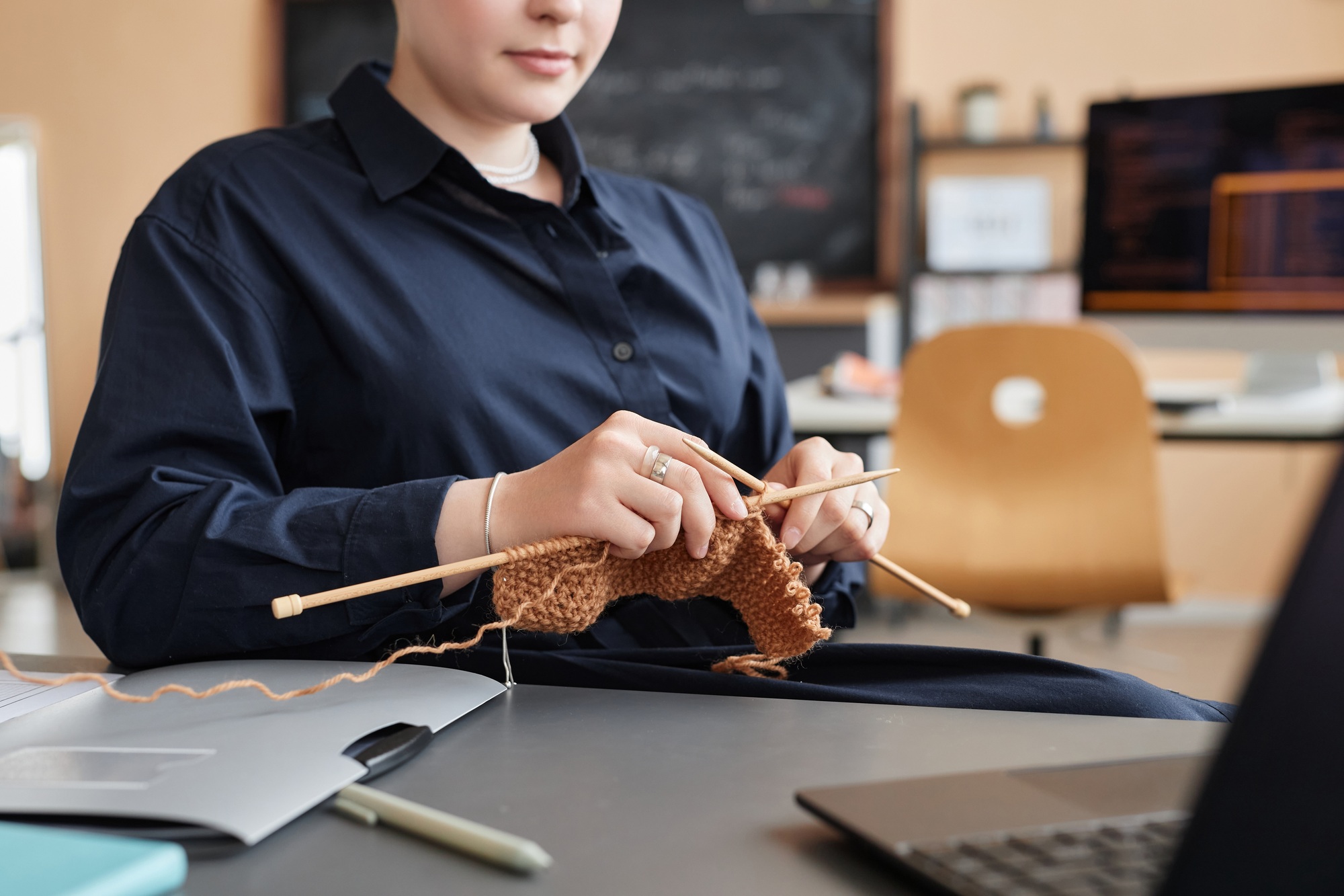 Young woman knitting or crocheting at workplace