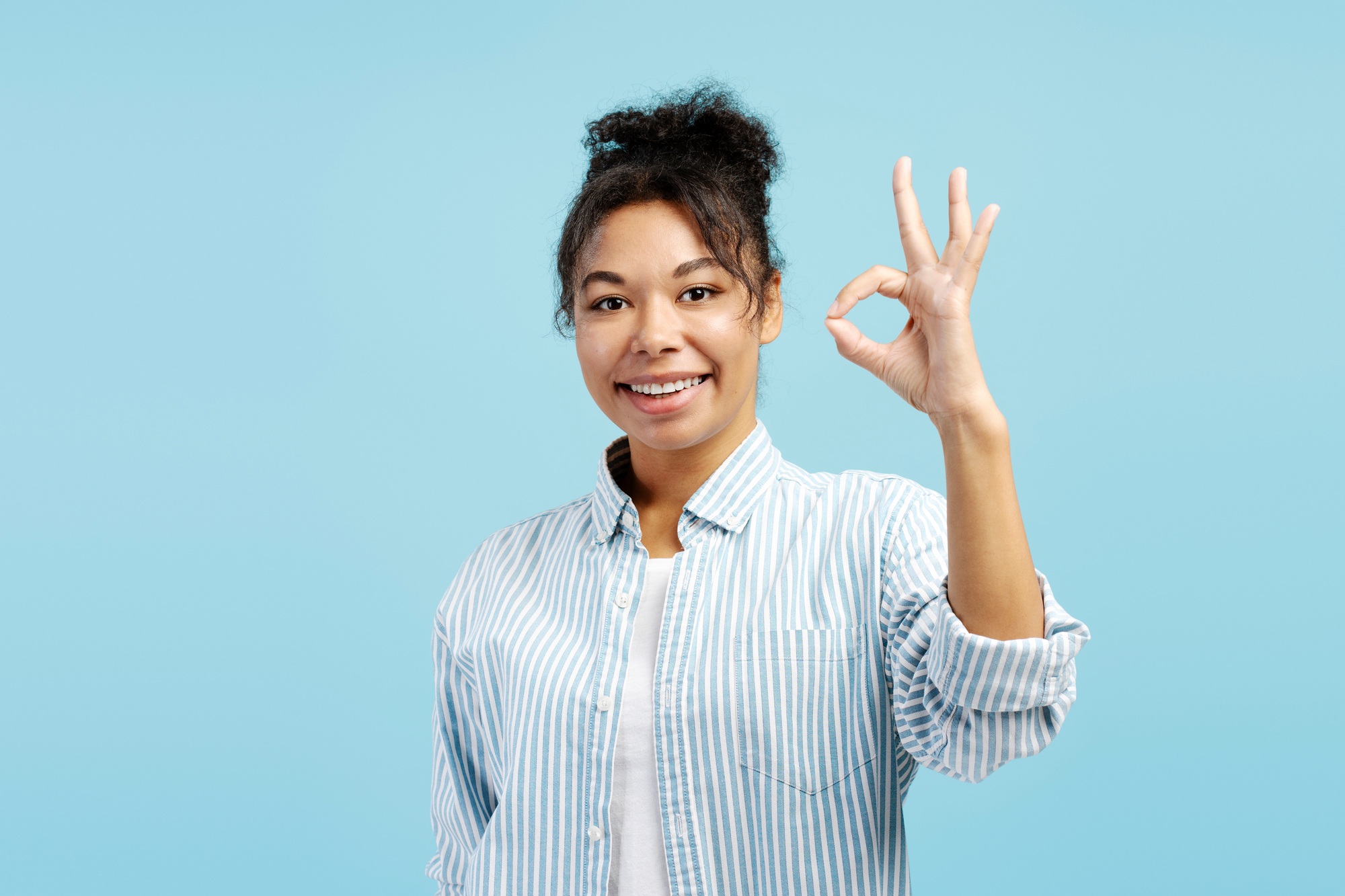 Young woman showing ok sign with hand gesture and smiling