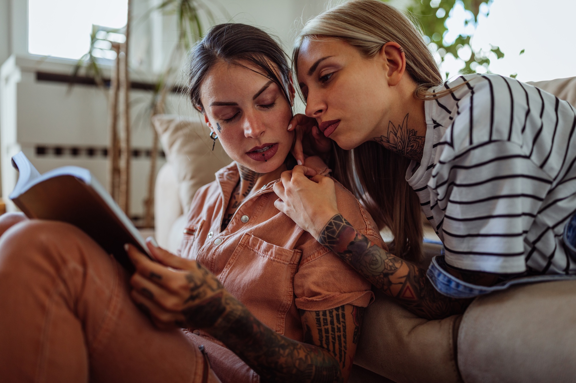 Young women reading a book together in living room