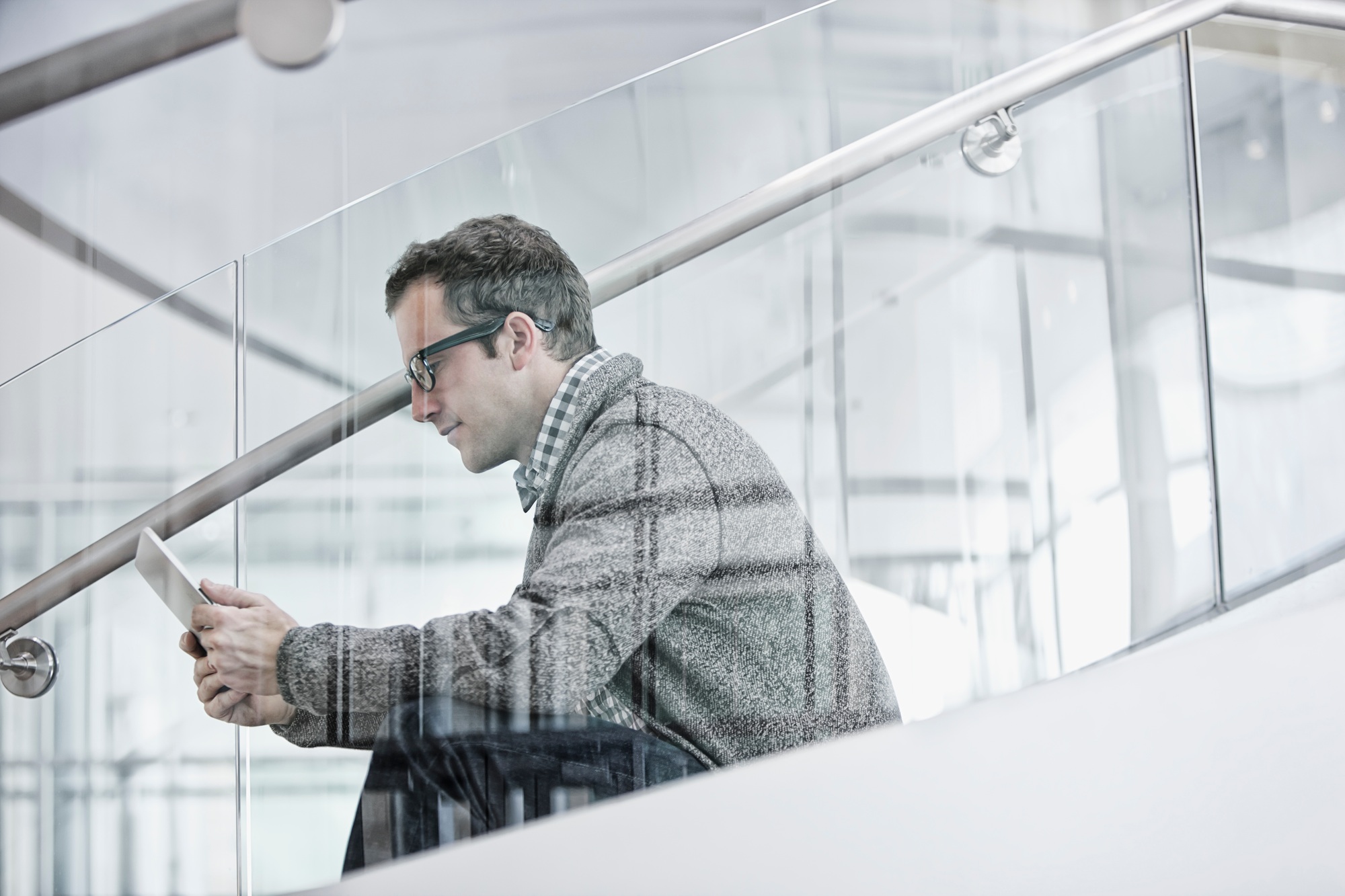A man seated on steps using a digital tablet.
