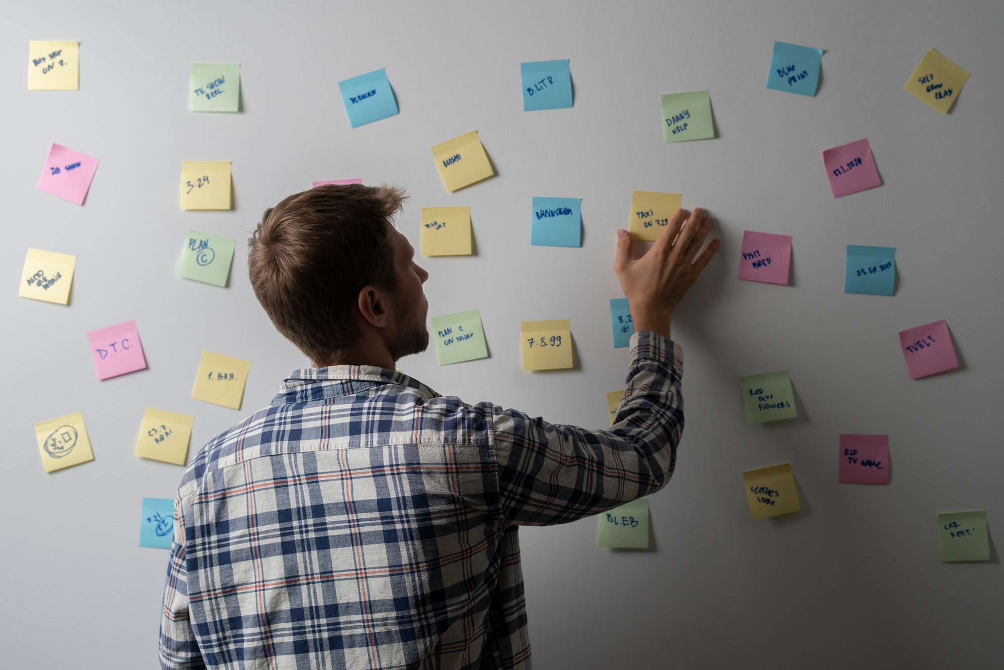 a person in office holds paper sticker and attach on the wall. job planing