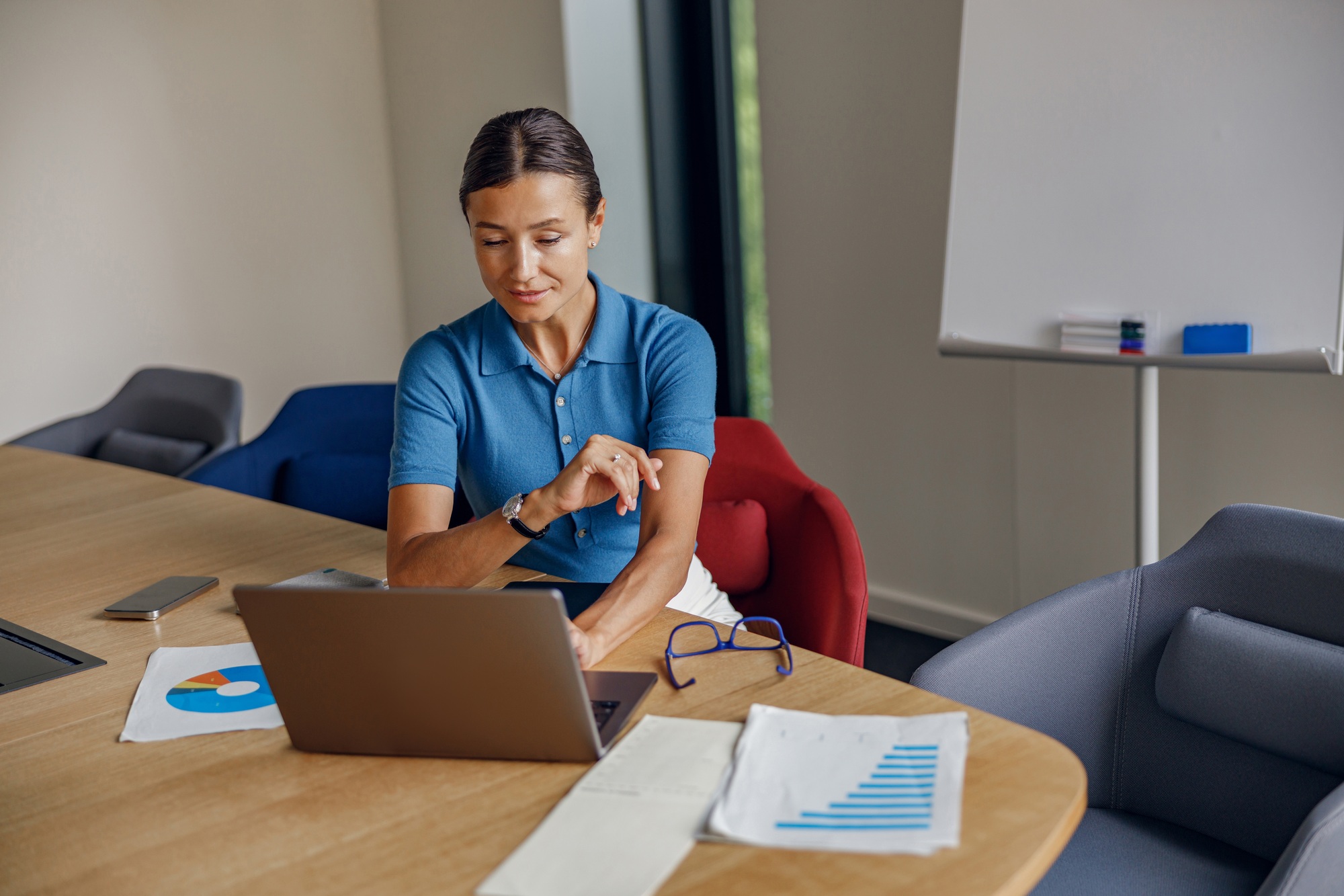 A Professional Woman Engaged in Work on a Laptop in a Modern and Stylish Office Setting