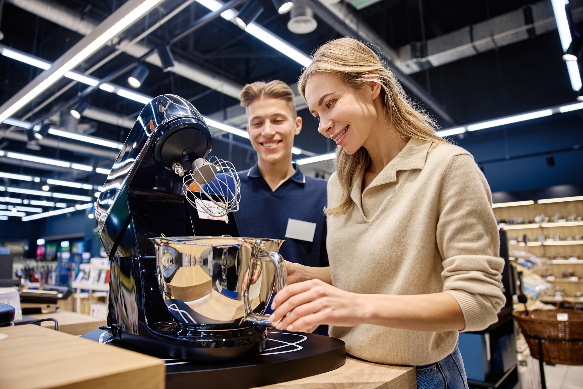 A Sales Associate showcases a kitchen appliance to customers, emphasizing its features
