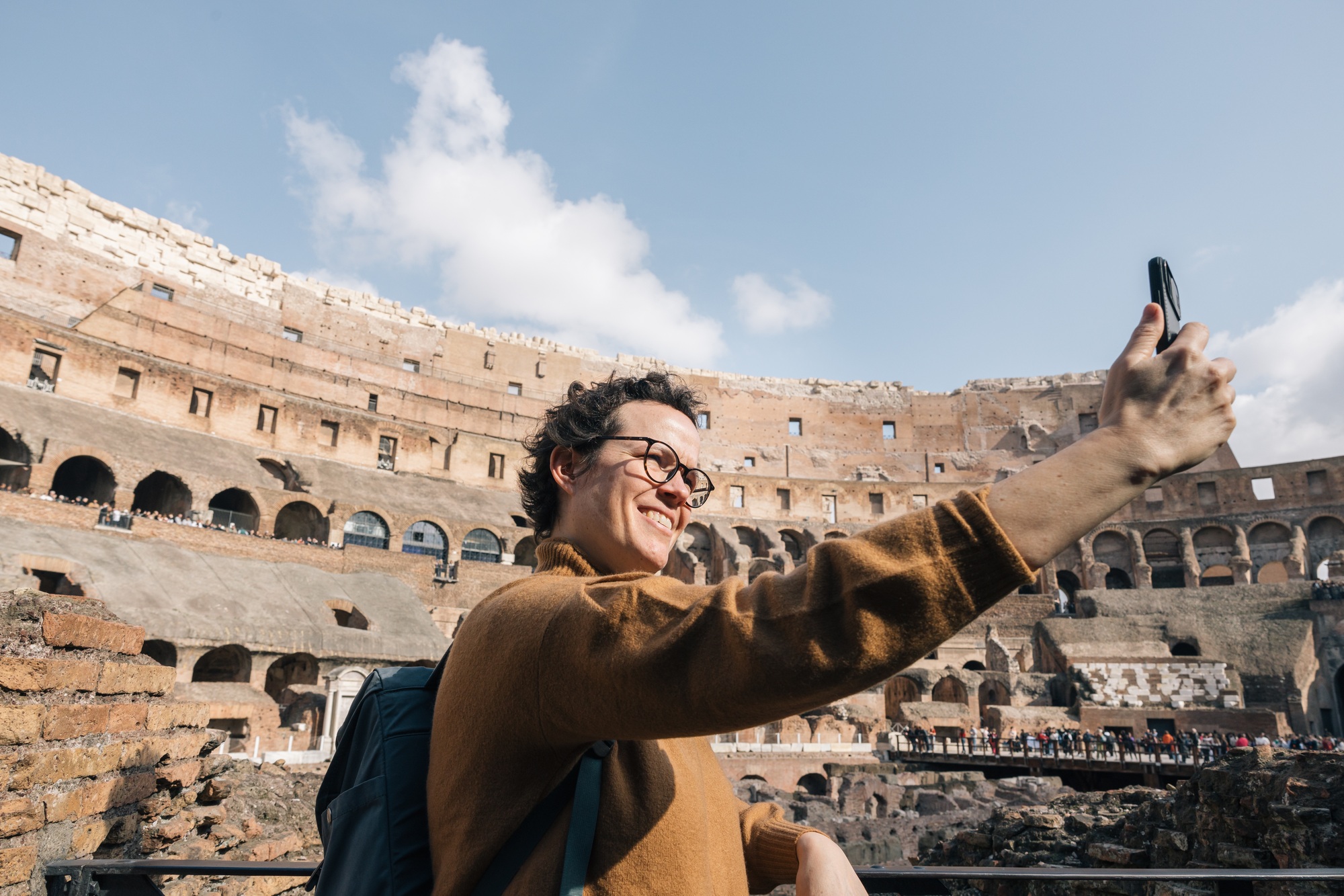 A woman is taking a selfie in front of the Colosseum