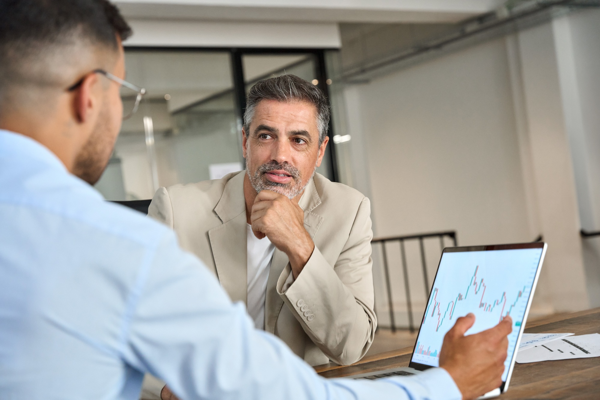 Advisor consulting stock market investor showing investment plan on laptop.
