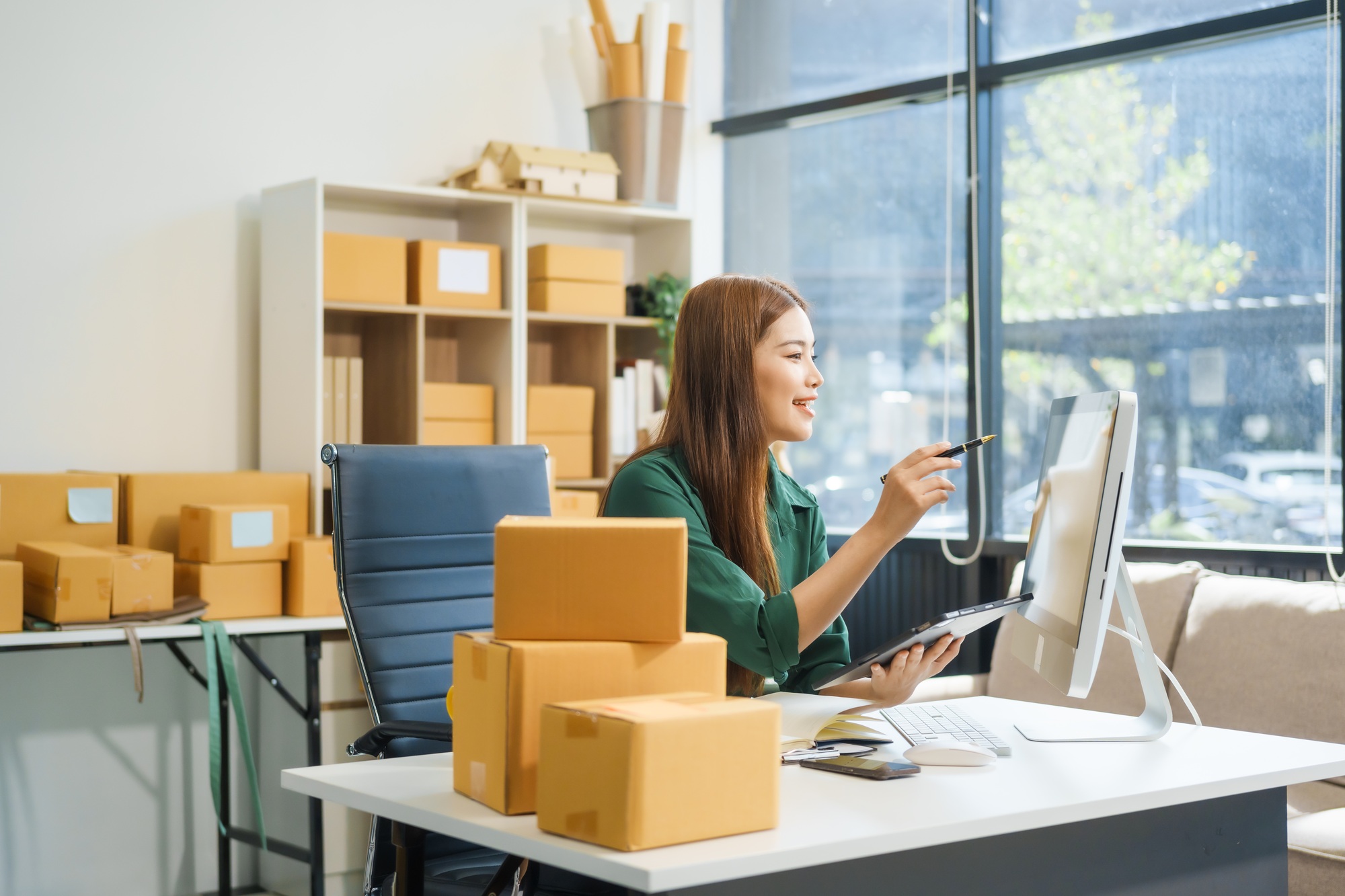 An Asian businesswoman sits at her desk, working on online sales e-commerce marketing strategies