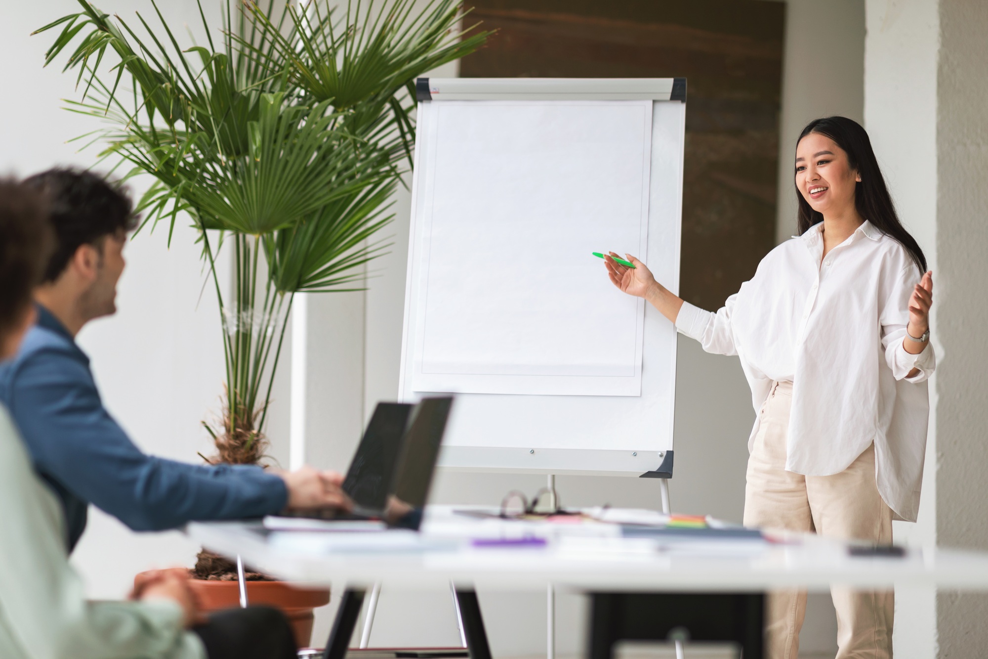 Asian Businesswoman Pitching Startup Idea To Coworkers In Modern Office