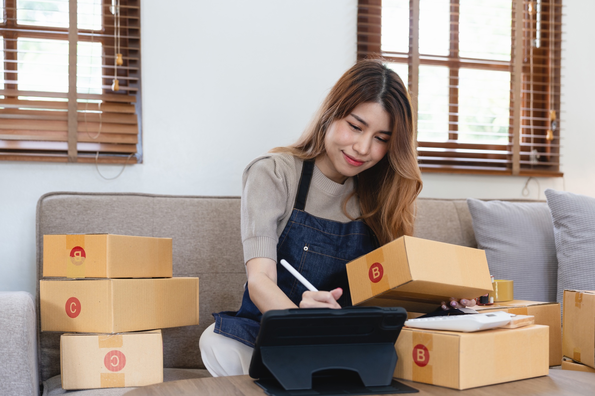 Asian woman freelancer sme business online shopping working with parcel box at home - SME business