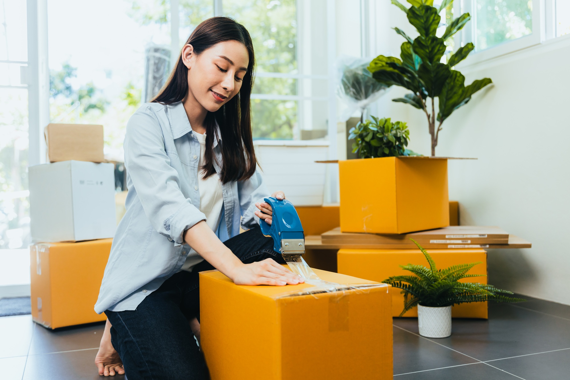 Asian woman packing box to move new home