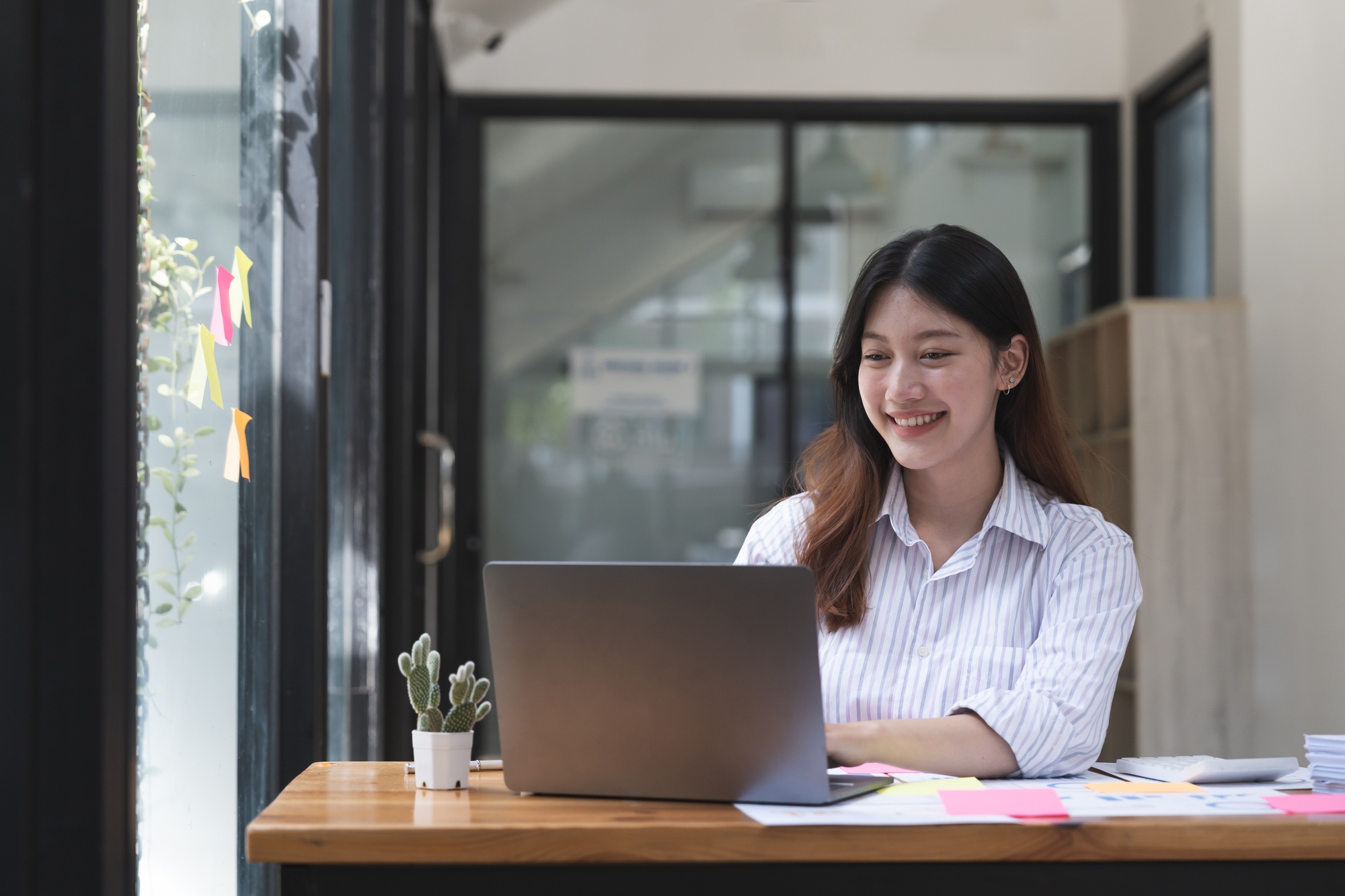Attractive asian woman working on laptop computer for accounting bookkeeping paperowork.