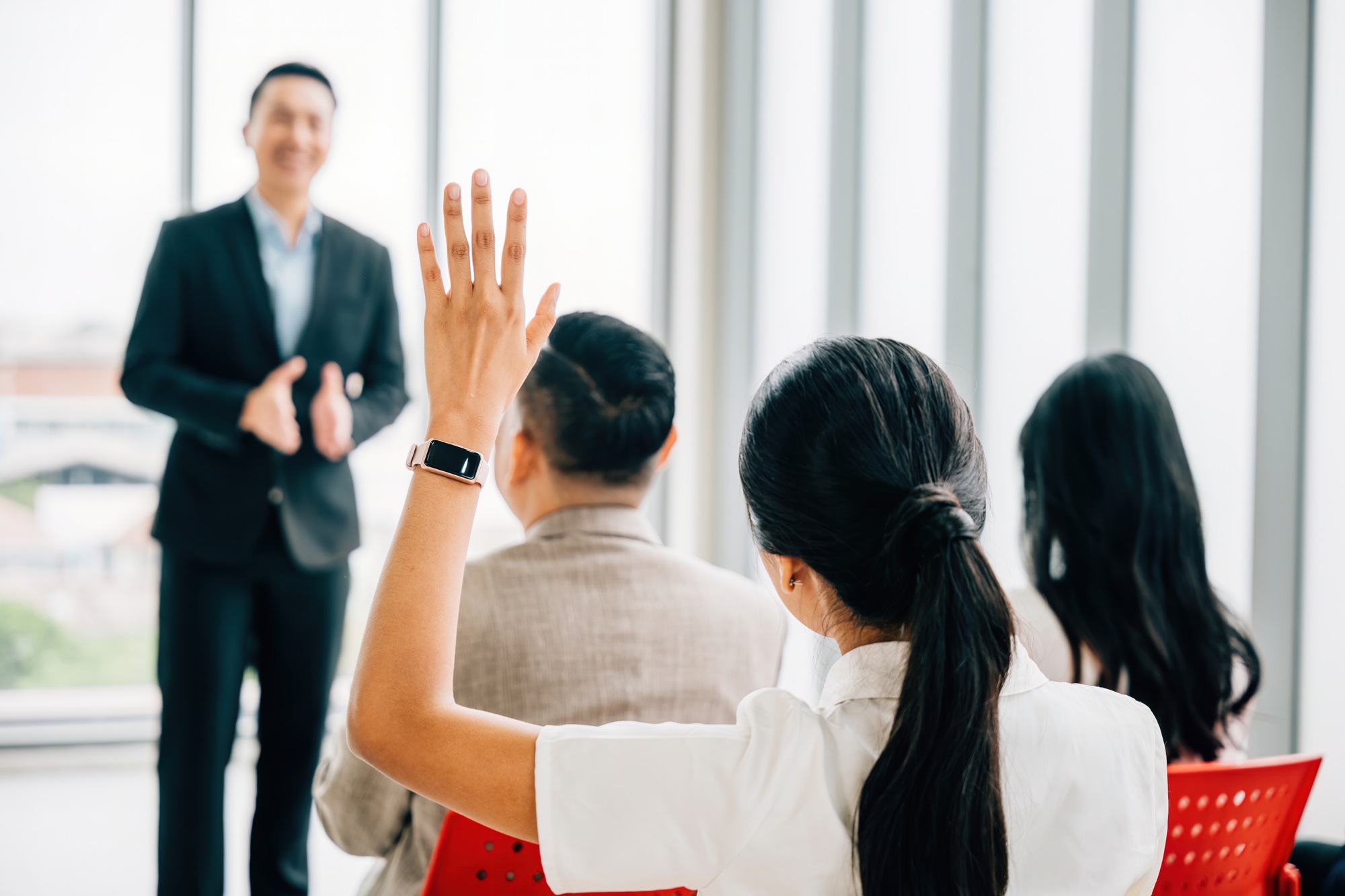 Audience engagement at a conference as hands are raised for questions, signifying the interactive