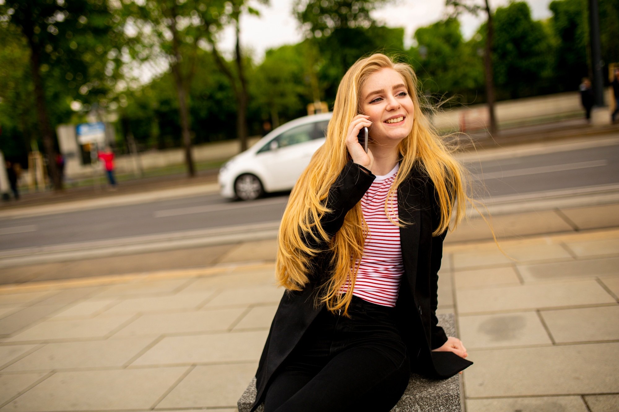 Beautiful smiling woman using mobile phone by Austrian Parliament in Vienna, Austria
