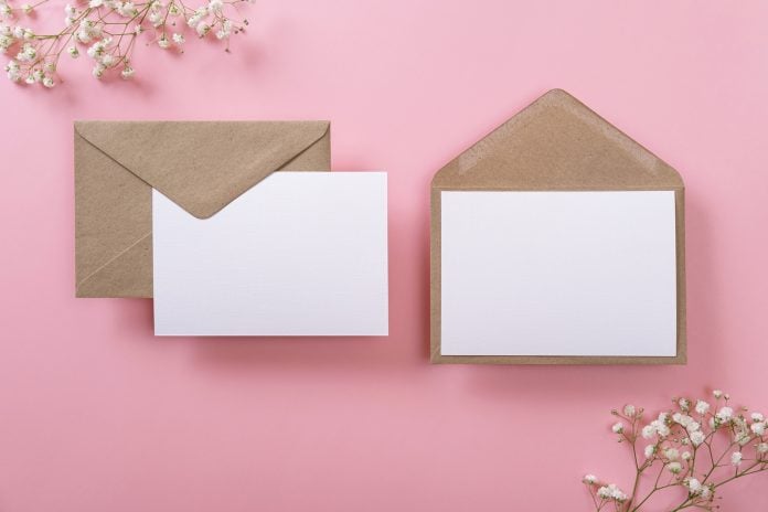 Blank greeting cards and envelopes with gypsophila on pink background.