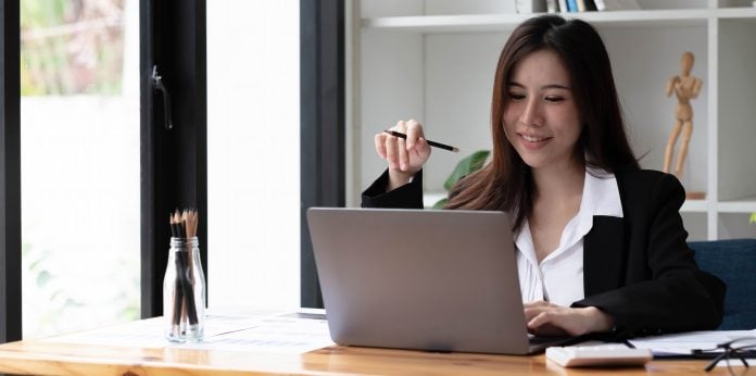 Business asian woman using laptop for do math finance on wooden desk in office, tax, accounting