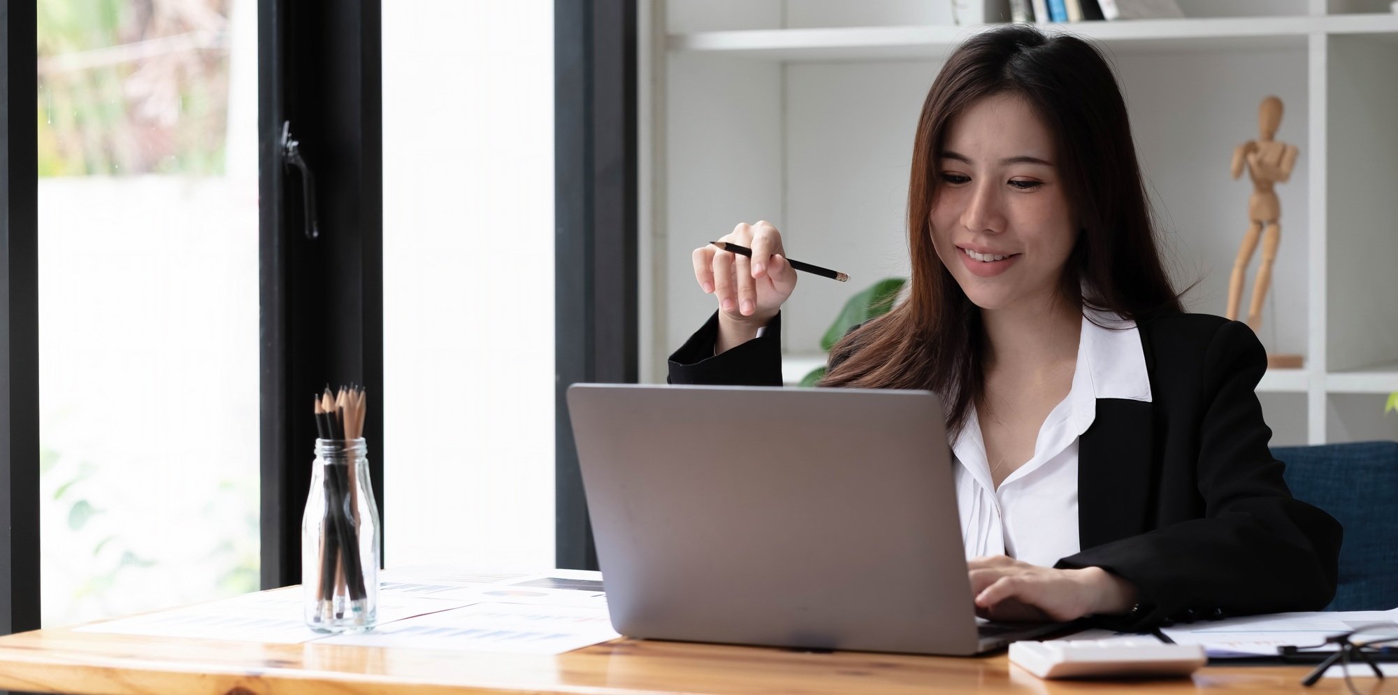 Business asian woman using laptop for do math finance on wooden desk in office, tax, accounting