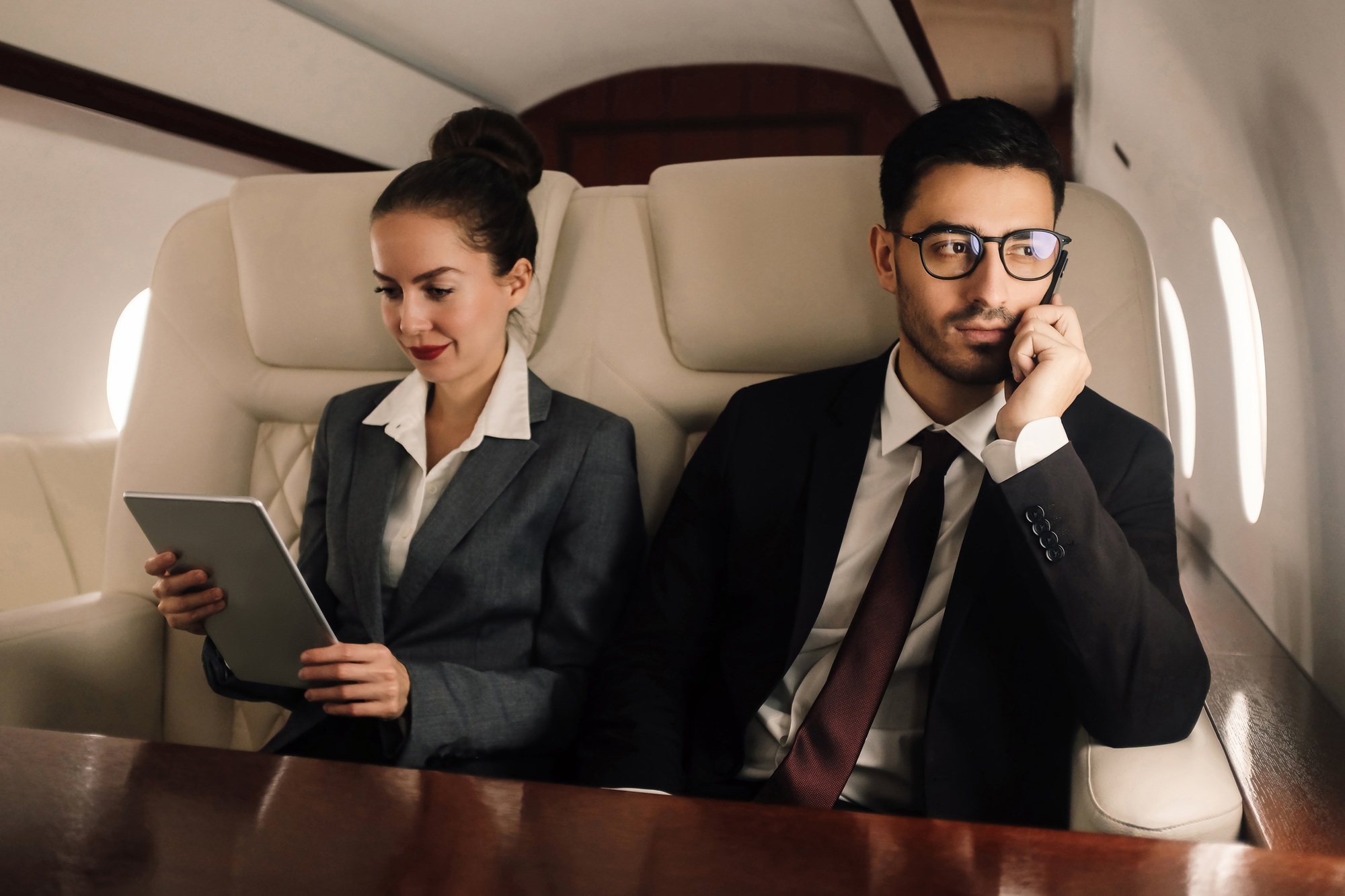 Business team working in private jet, man is talking on smartphone
