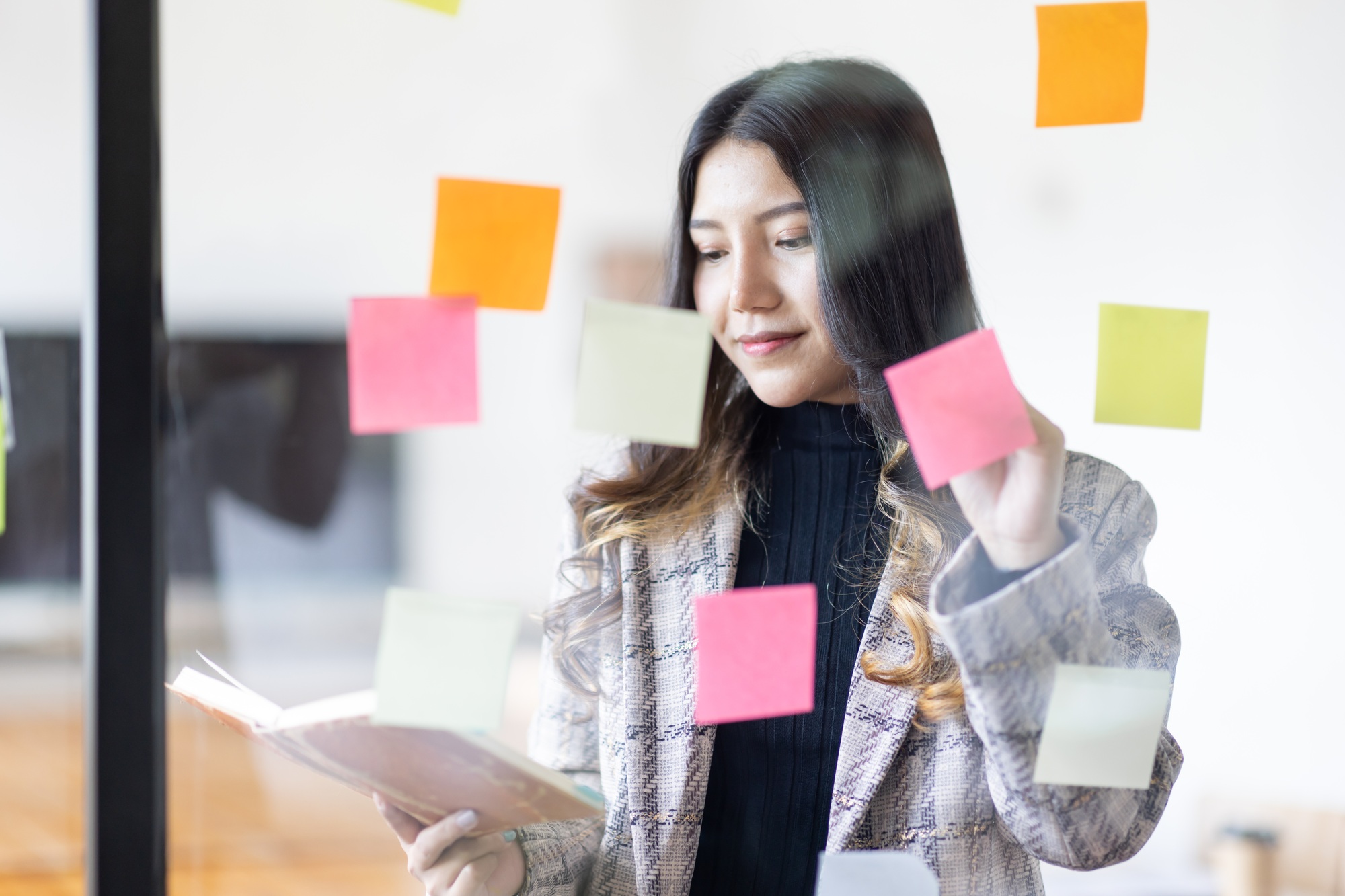 business young Asian women working on wall glass with post it stickers