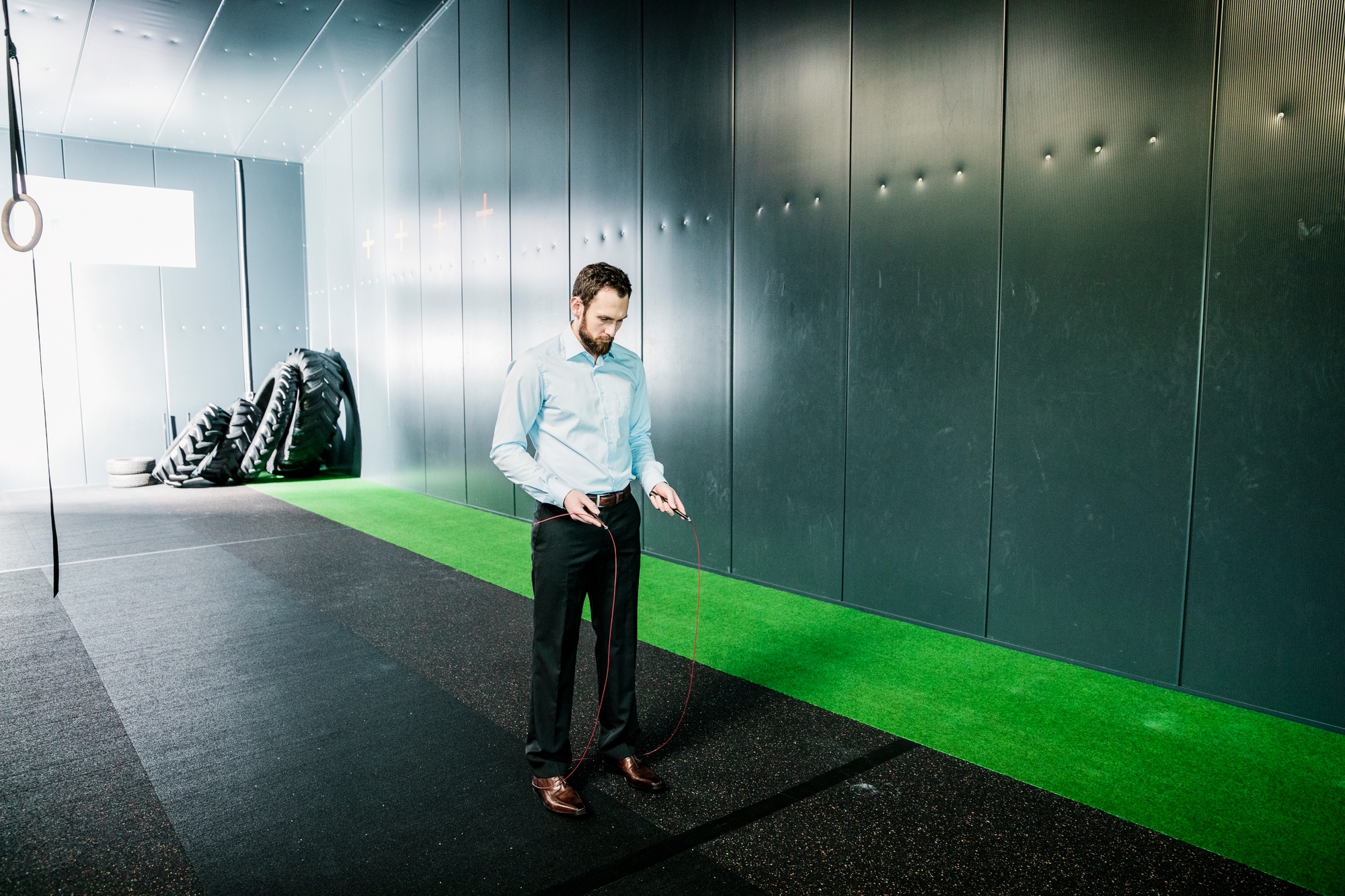 Businessman in gym looking at skipping rope