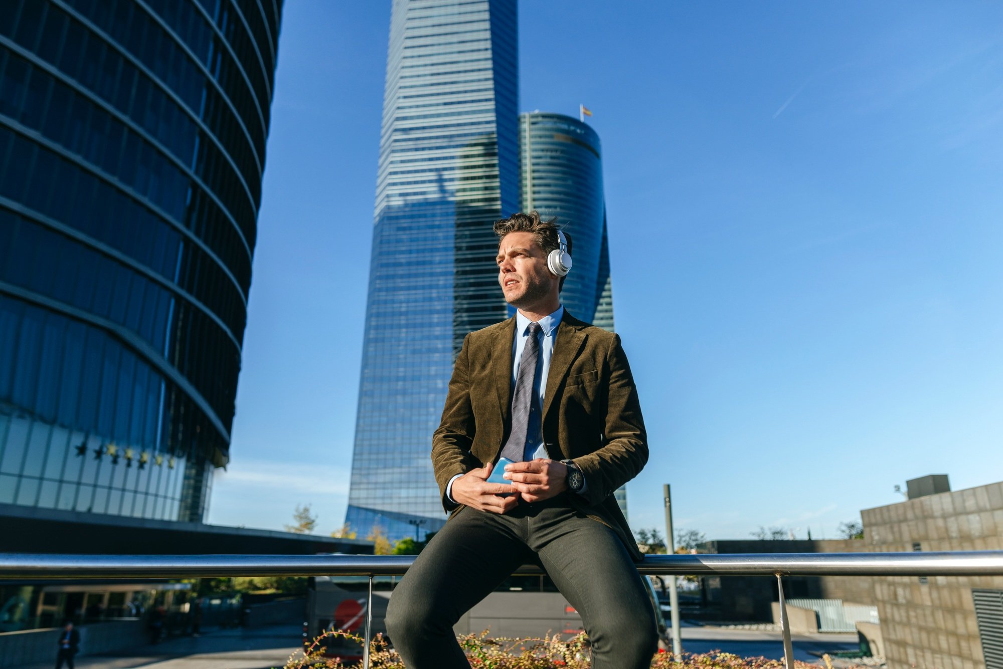 Businessman listening music with headphones in cuatro torres business area