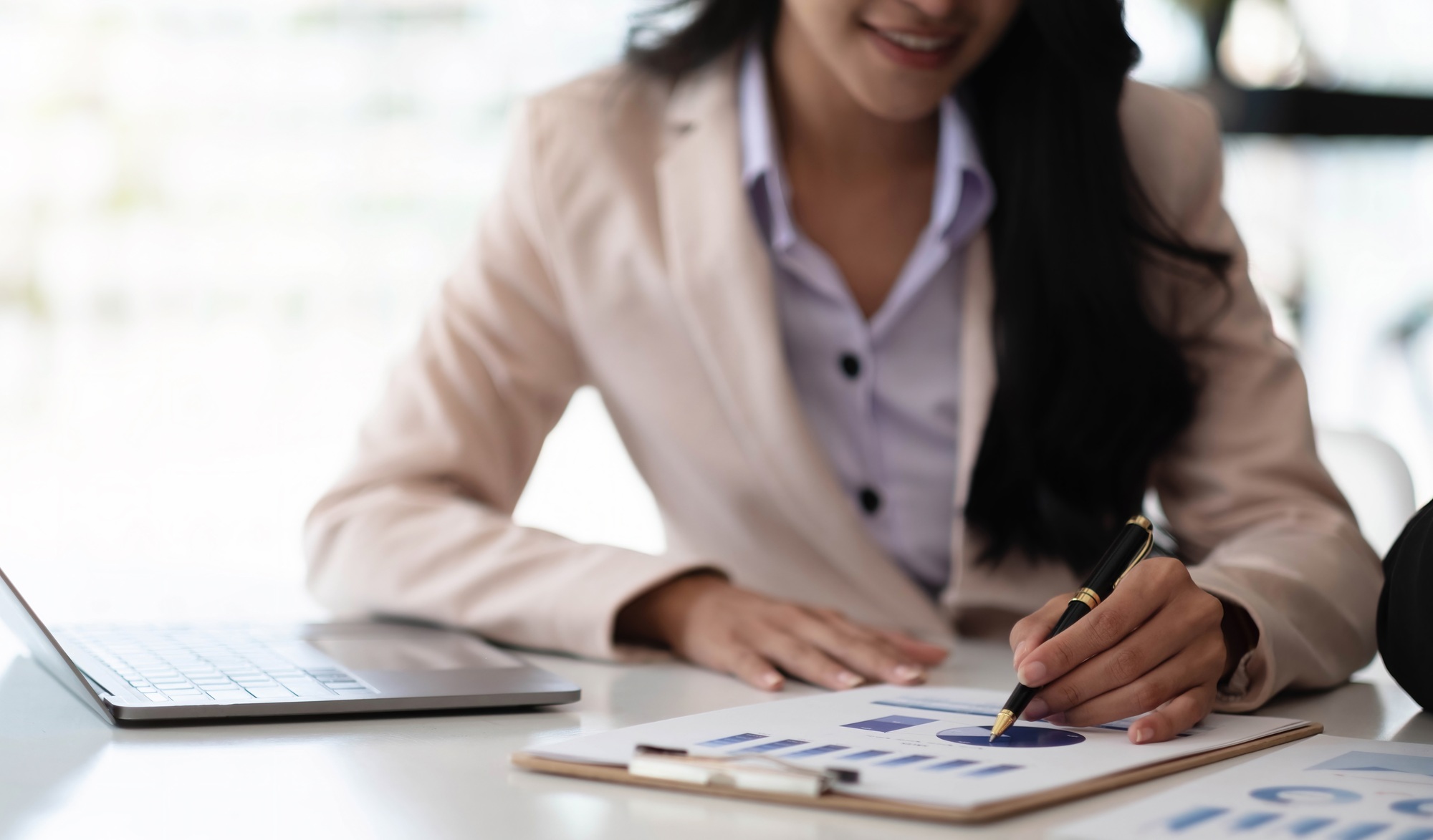 Businesswoman pointing pen at data graph, estimating profit and income statement of business in