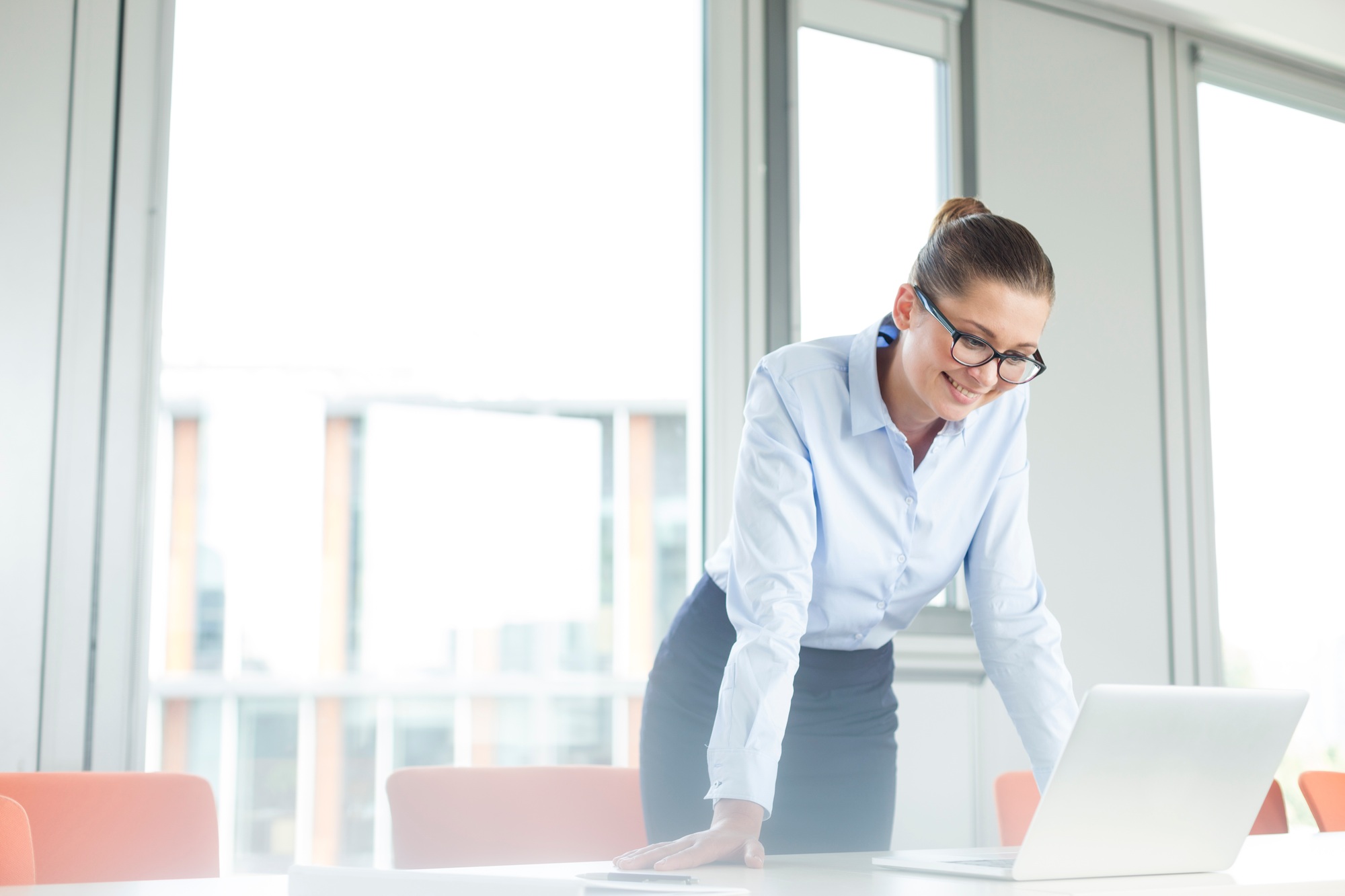 Businesswoman standing at desk reading emails