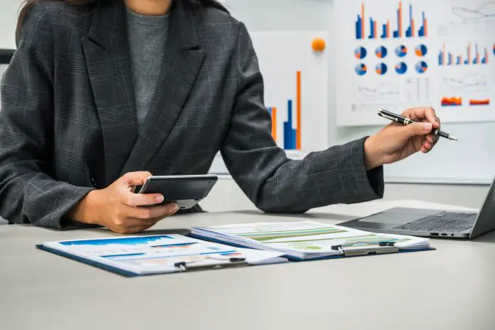 businesswoman works diligently at her desk, reviewing financial documents and analyzing investment