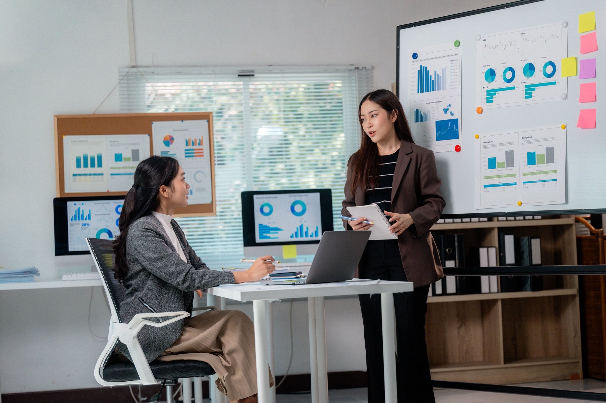 Businesswomen discussing marketing strategy using charts and graphs, analyzing sales performance