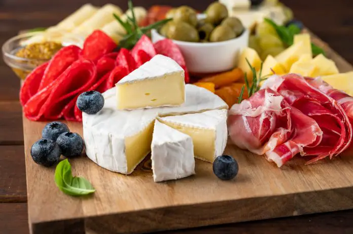 Charcuterie board with a variety of cheeses, salami, chorizzo, prosciutto, nuts, bread, berries