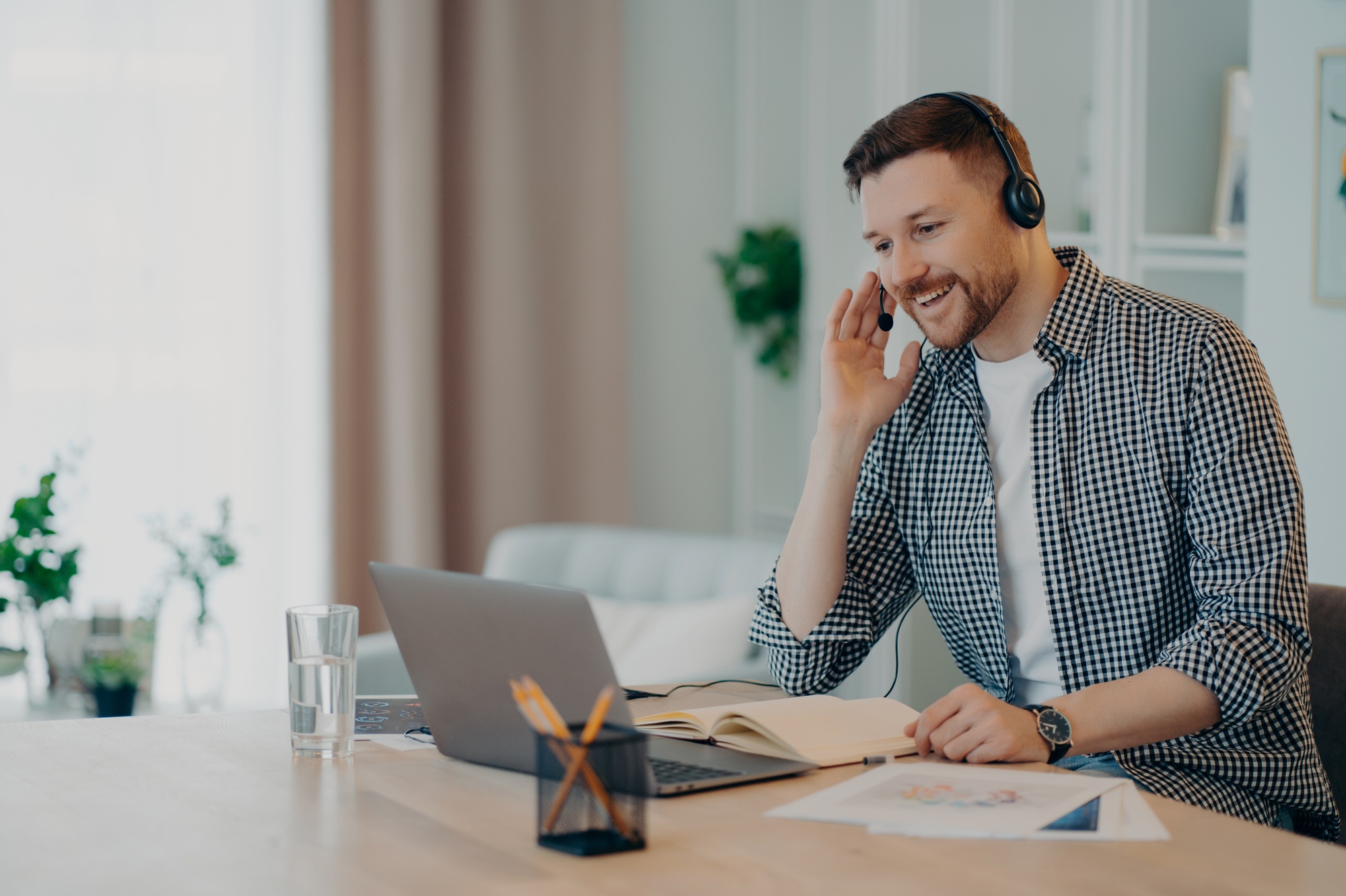 Cheerful man participates in self improvement webinar wears checkered shirt communicates online